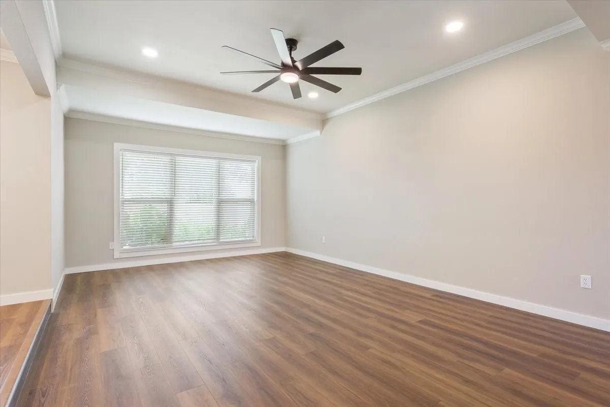 Spacious room featuring vaulted ceilings, wood-finish flooring, a large window with blinds, recessed lighting, and a remote controlled ceiling fan