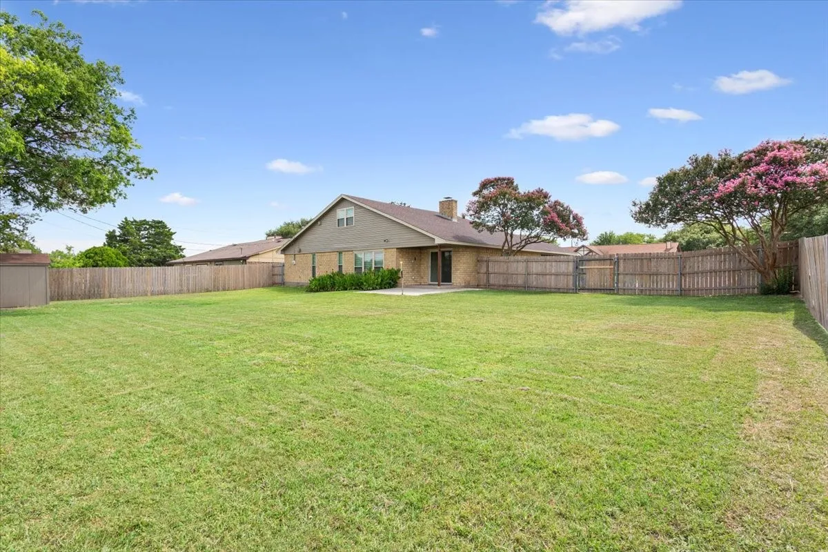Expansive green lawn with a full privacy fence