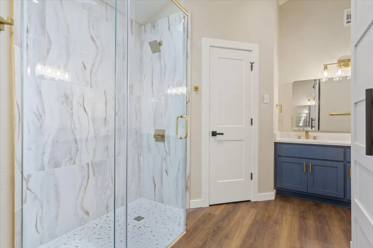 Primary ensuite bathroom custom glass-enclosed shower with large format marble-look tile walls and a mosaic tile floor