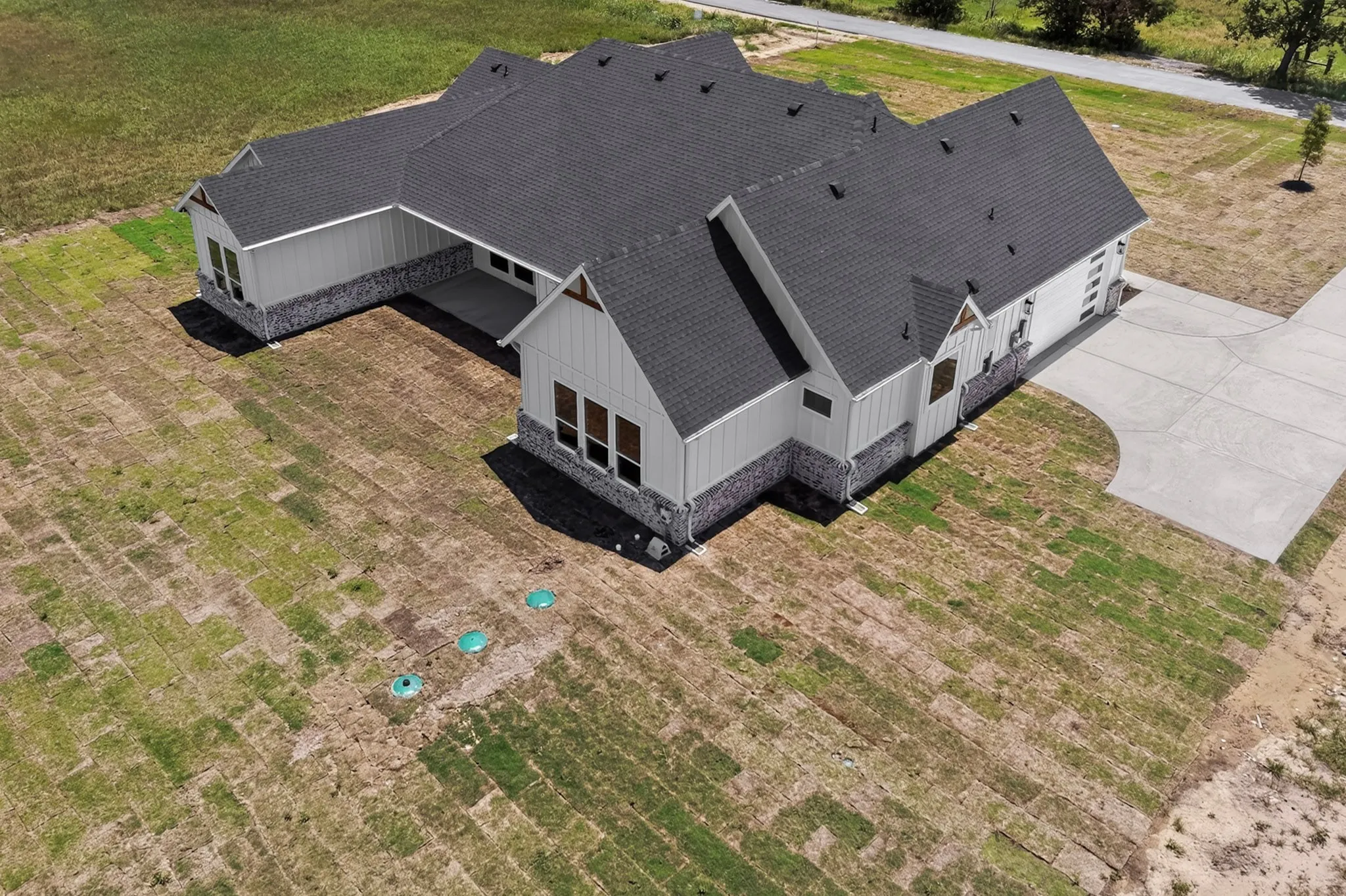 Modern farmhouse exterior featuring vertical white siding, stone accents, a dark shingle roof, and multiple gables