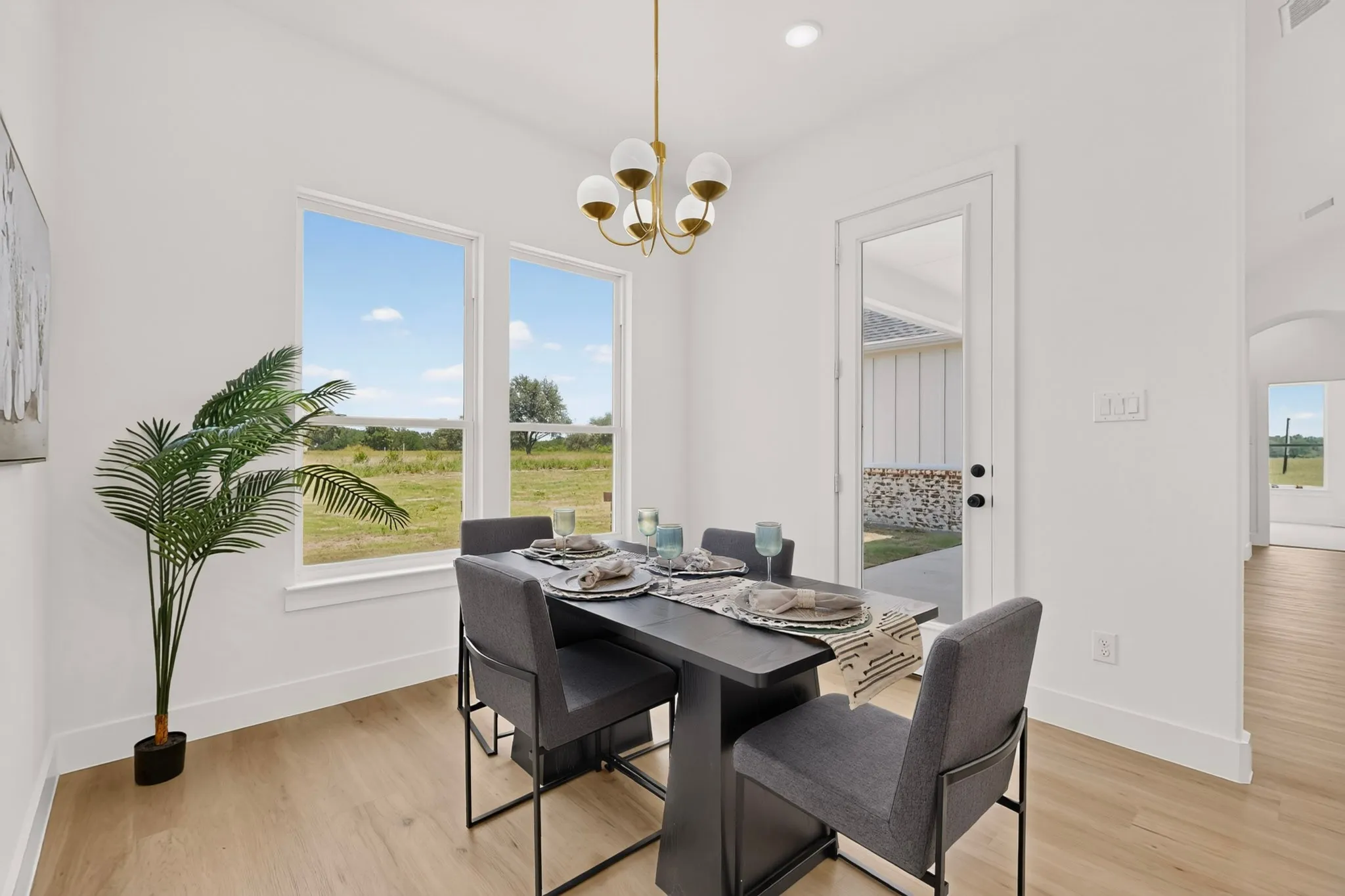 Dining area with light wood-finish flooring, featuring a modern chandelier and multiple windows
