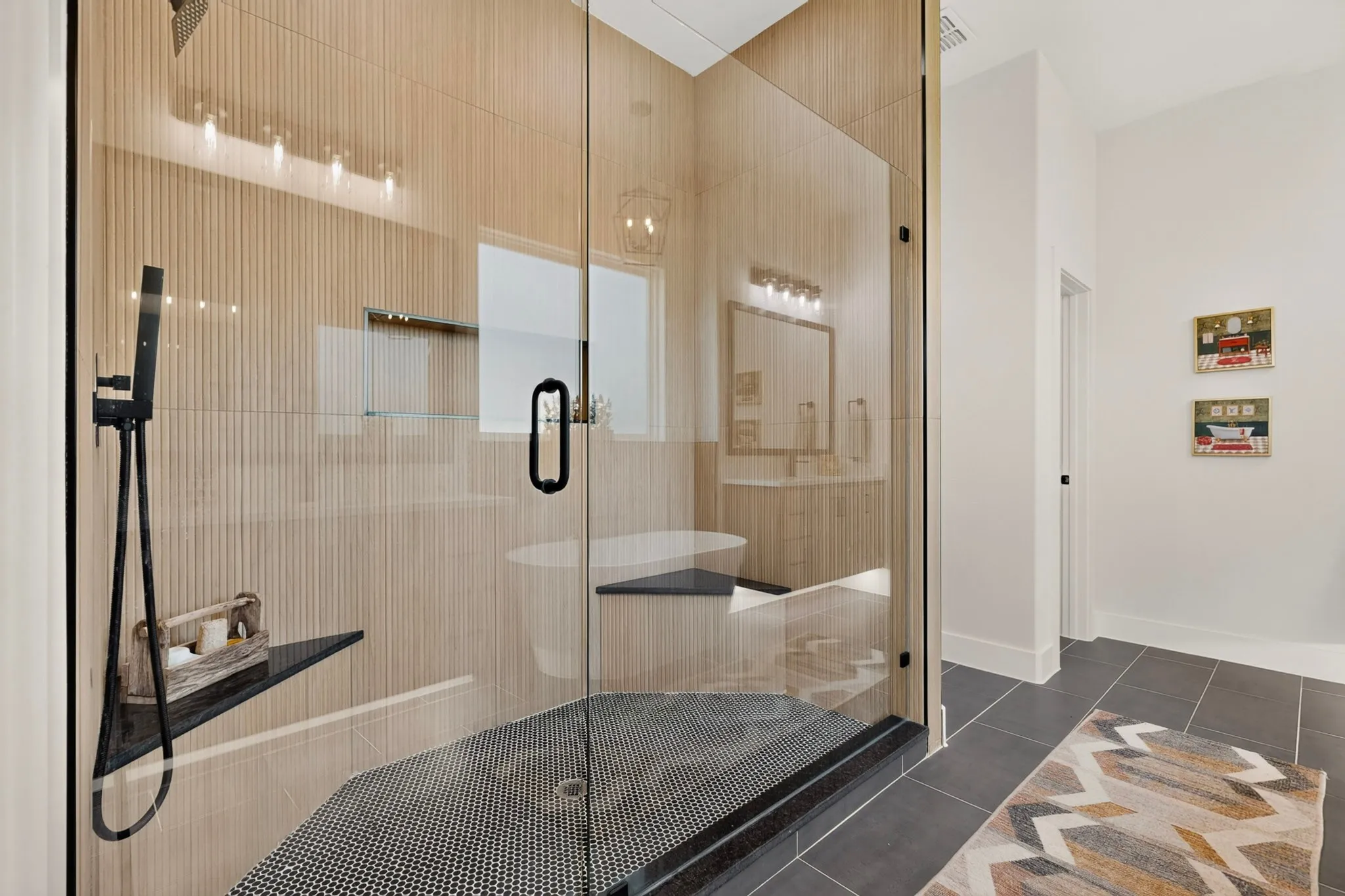 Glass-enclosed shower featuring a black hex-tile base, a built-in black corner shelf, and matte black shower fixtures