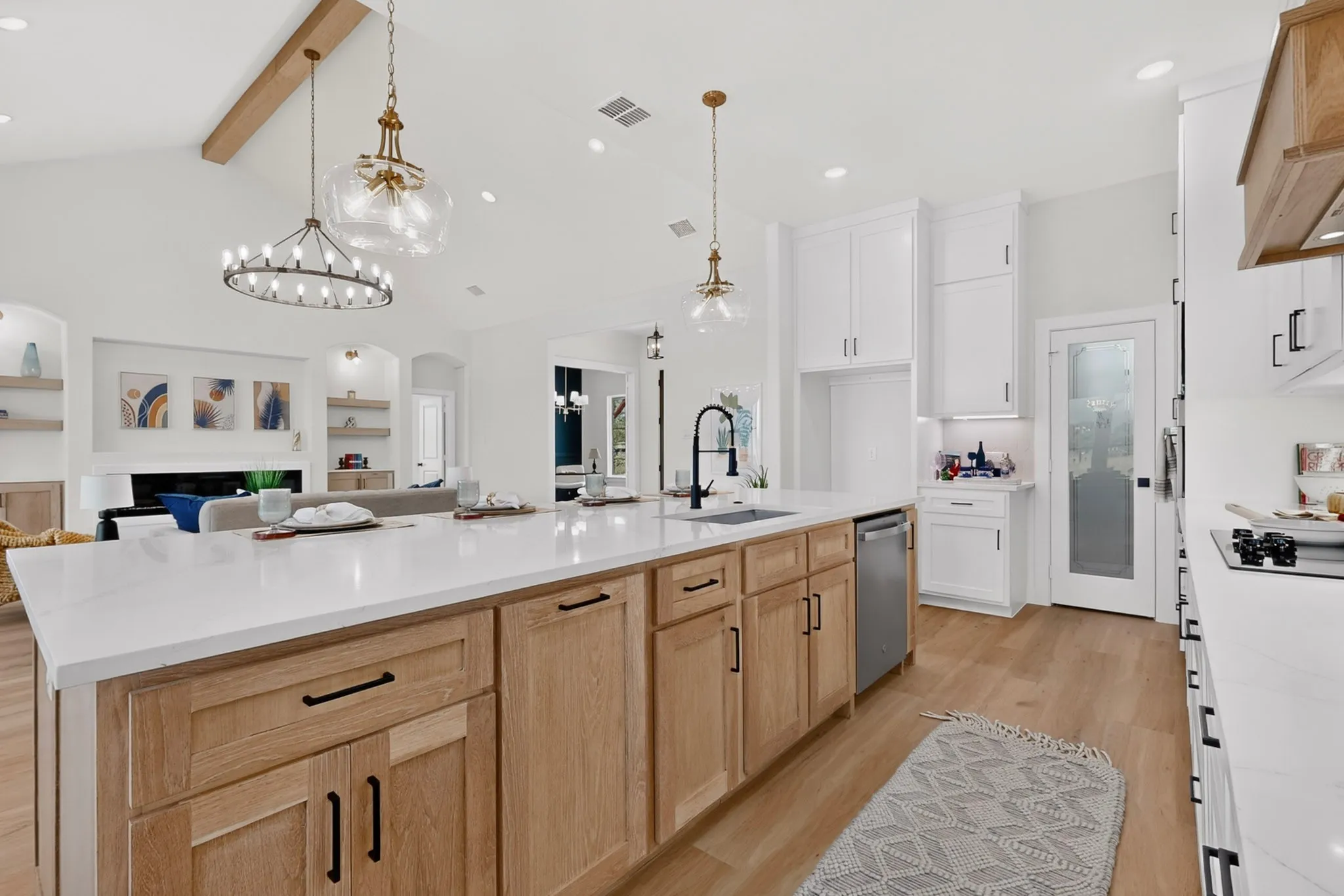 Spacious kitchen island with light wood-finish cabinetry, white countertops, and a built-in sink with a matte black faucet