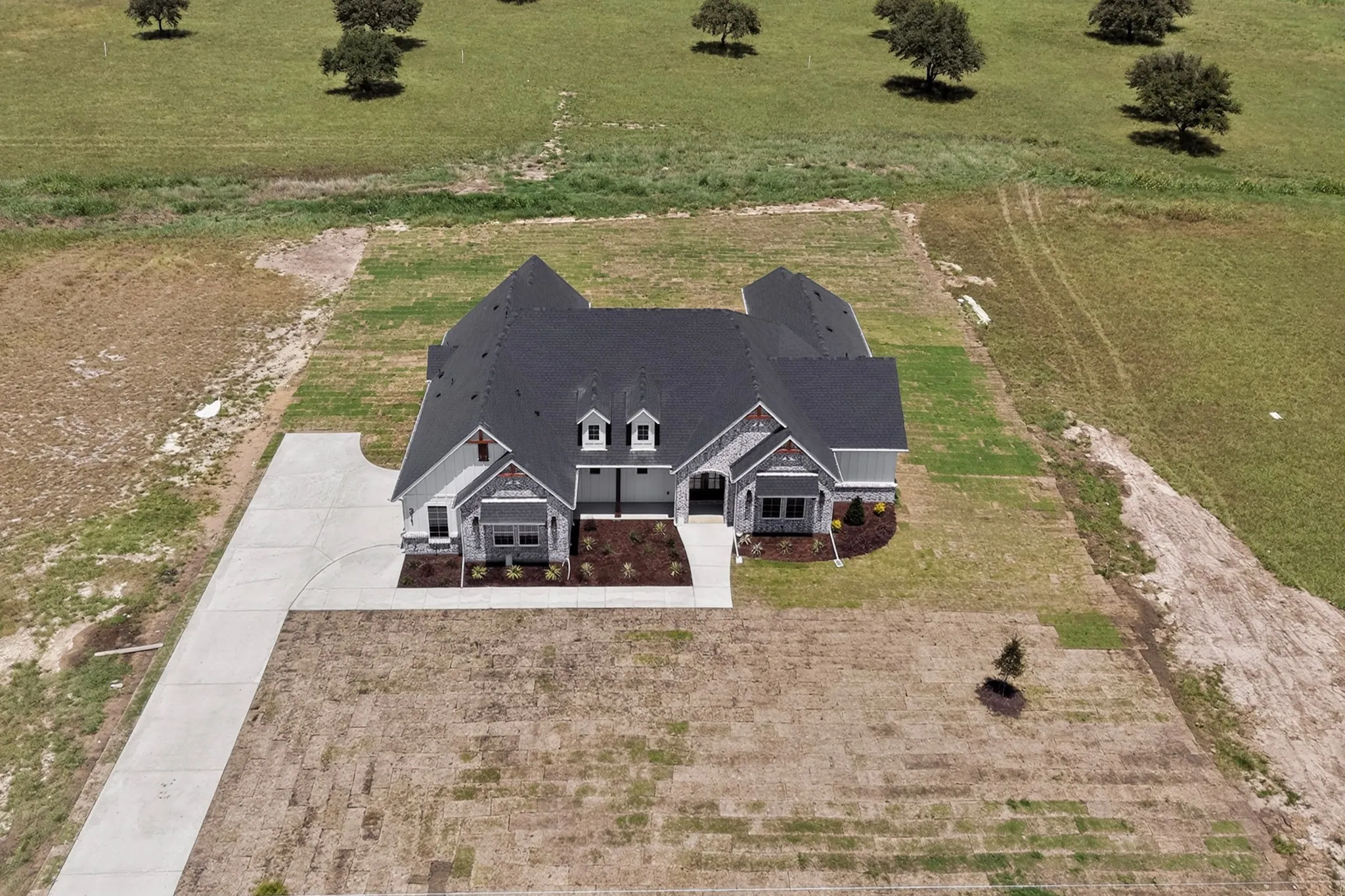 Exterior featuring a dark shingle roof, light gray siding, stone accents, and a concrete driveway