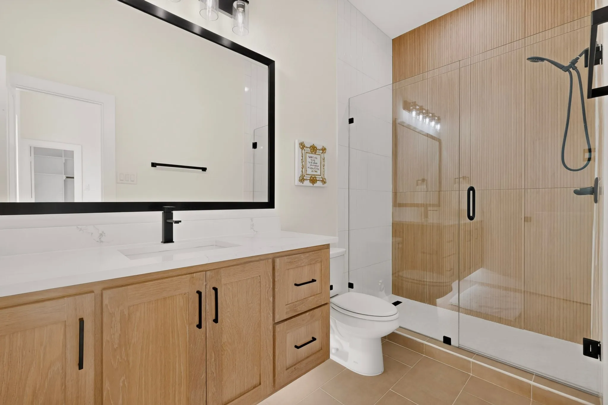 Modern bathroom featuring a wood-finish vanity with a white countertop and integrated sink