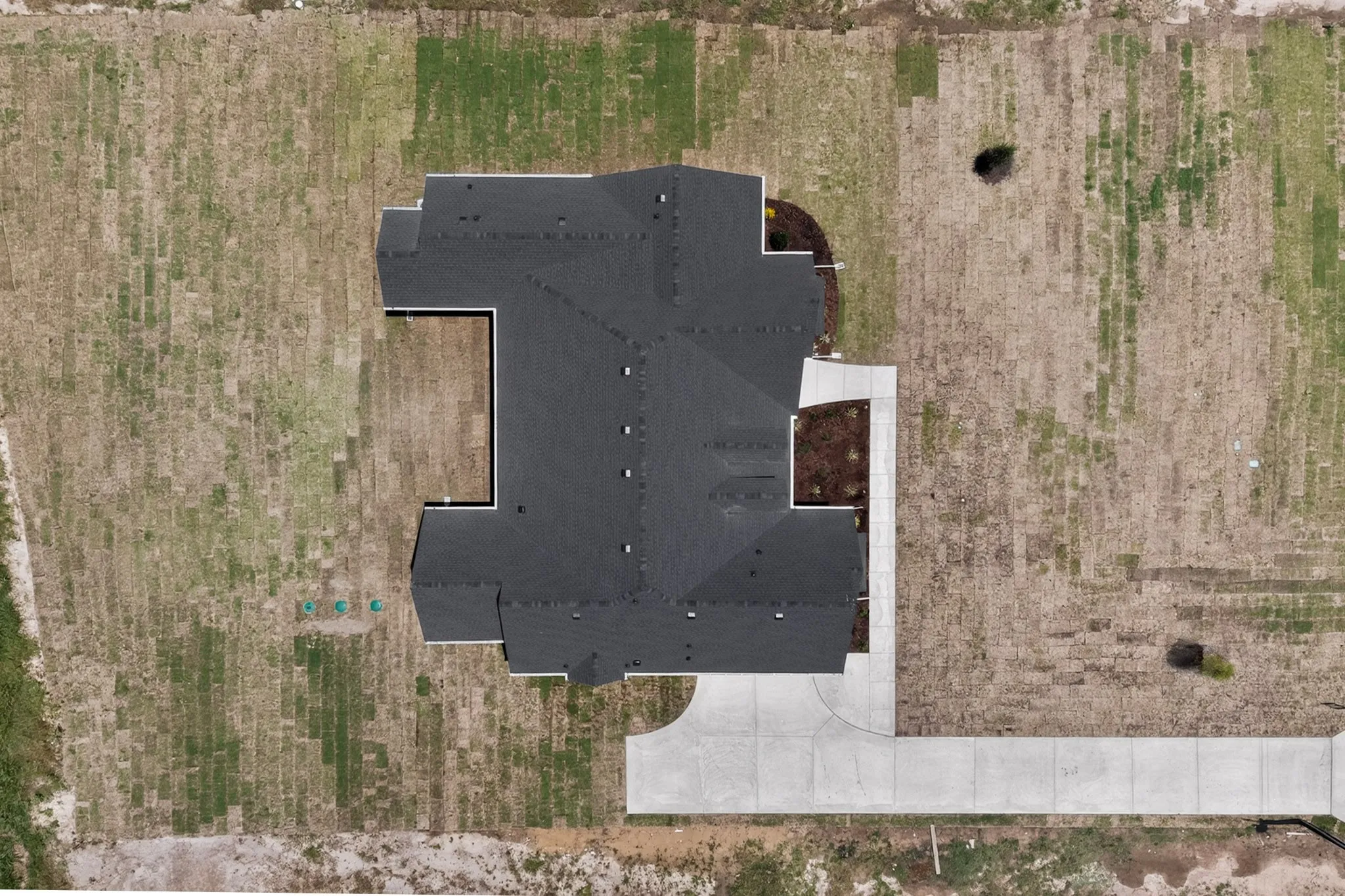Newly constructed residence featuring a dark shingle roof and a concrete driveway