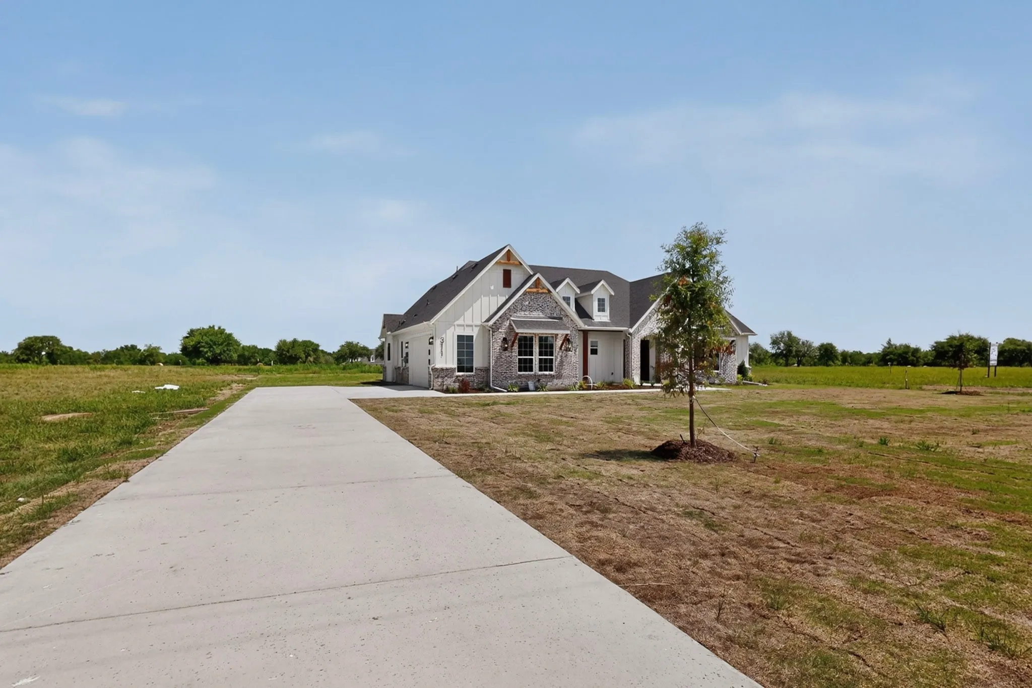 Modern farmhouse exterior featuring board and batten siding, stone accents, and a dark shingle roof