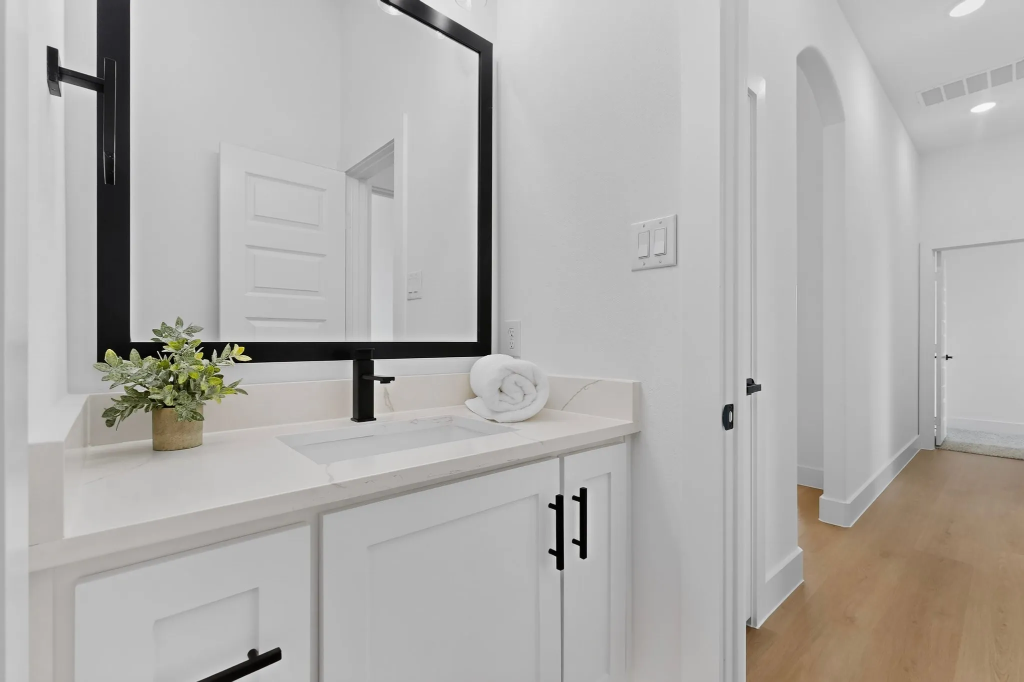 Bathroom vanity featuring a rectangular undermount sink, a light-toned countertop, and white cabinetry with matte black hardware