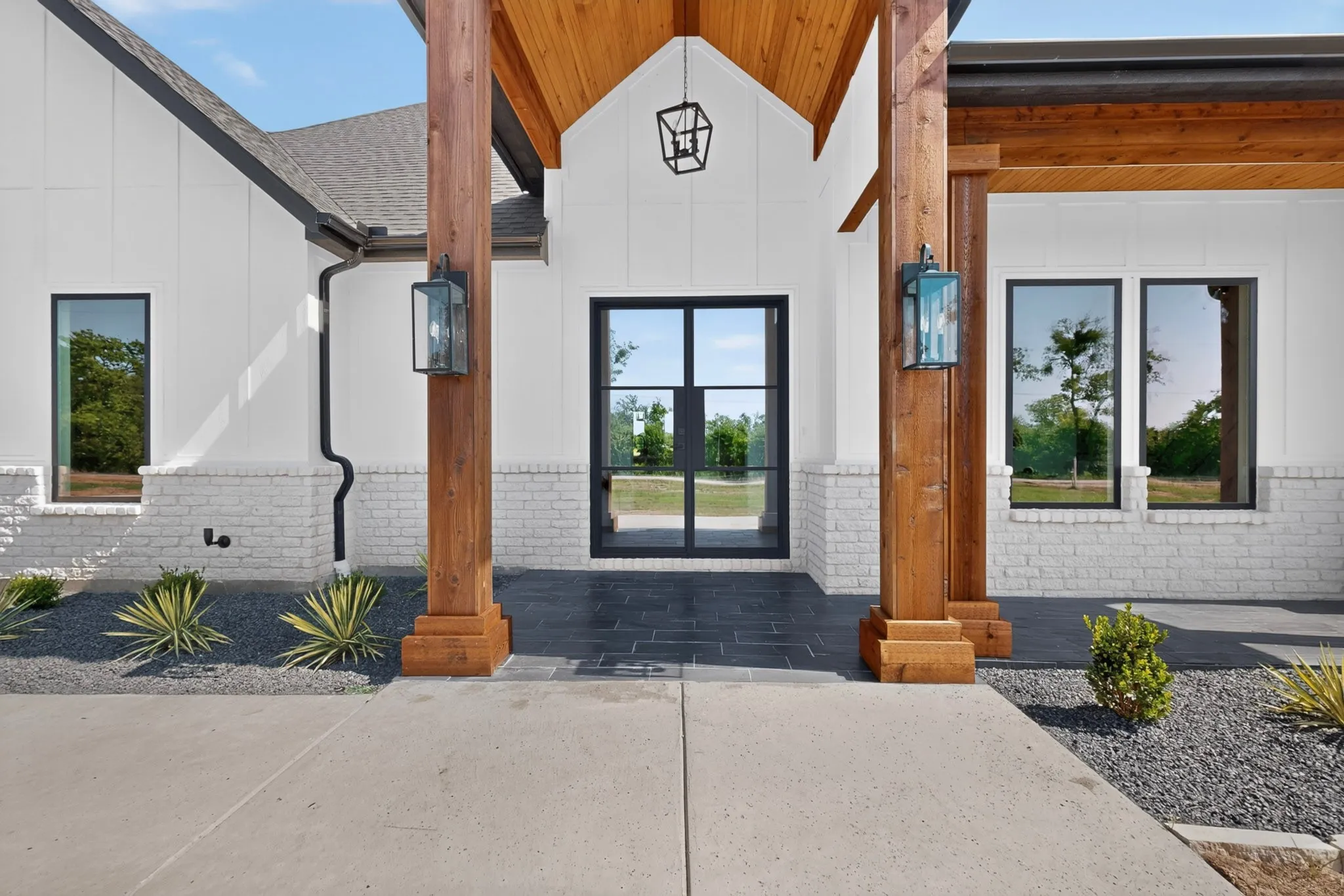 Modern farmhouse exterior featuring a black framed double-door entry