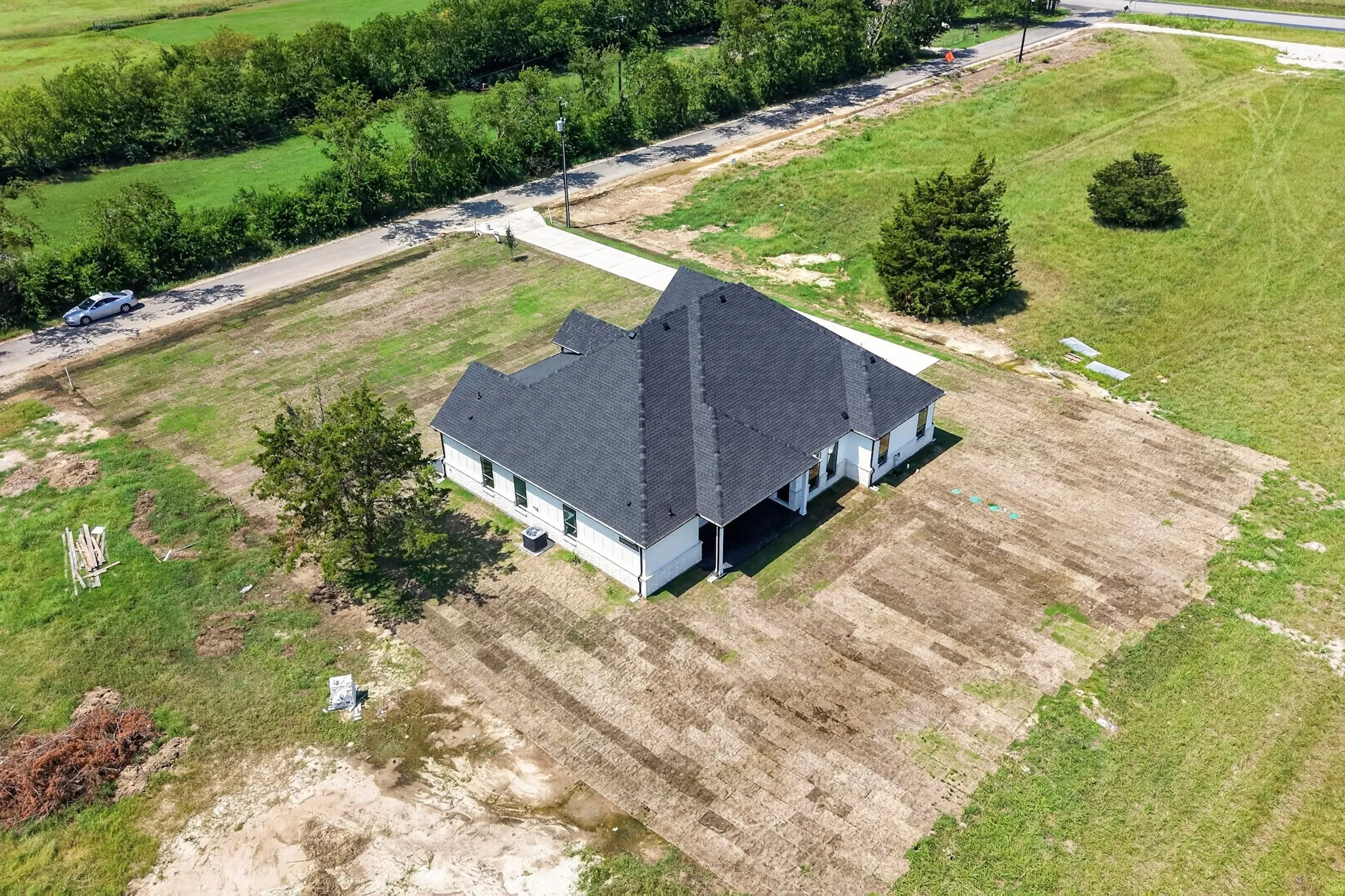 Newly constructed residence featuring a dark shingle roof, white siding, and a concrete driveway