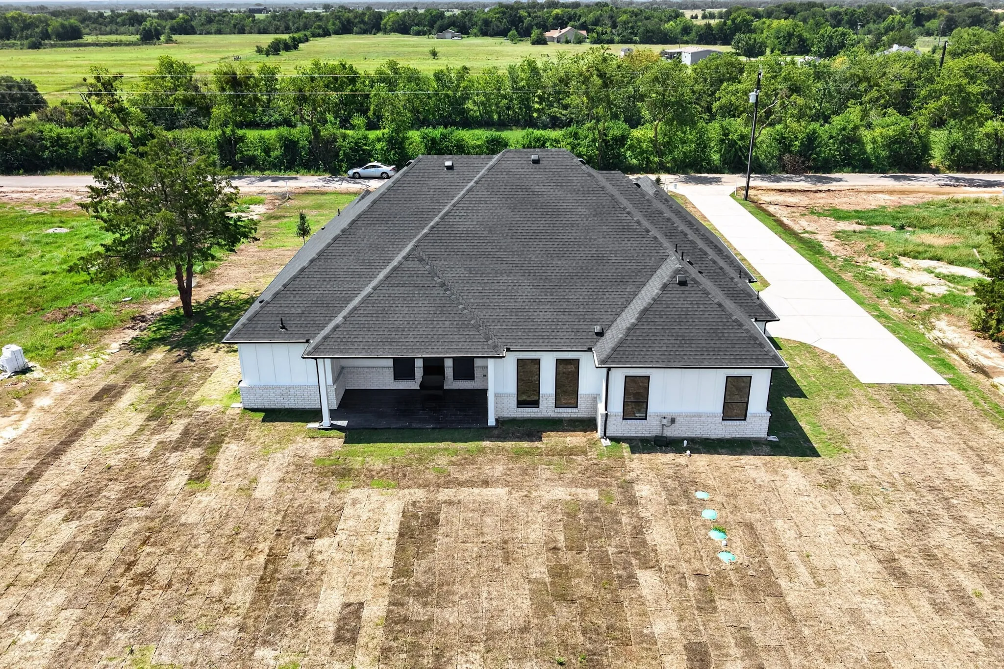 Modern single-story residence featuring a dark shingle roof, white siding, and a light stone skirt