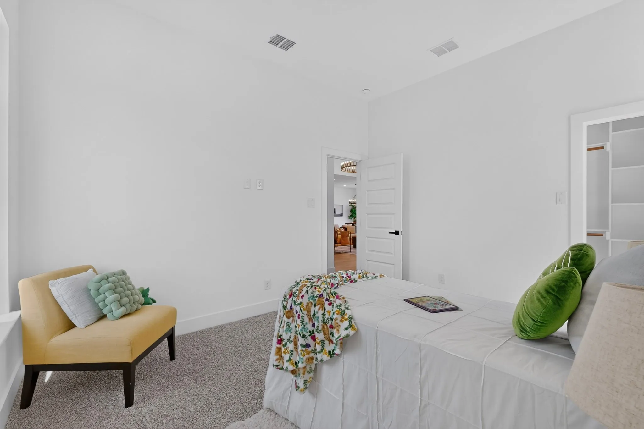 Bright interior space featuring white walls, textured carpeting, a white paneled door with matte black hardware, and an integrated closet system with shelving