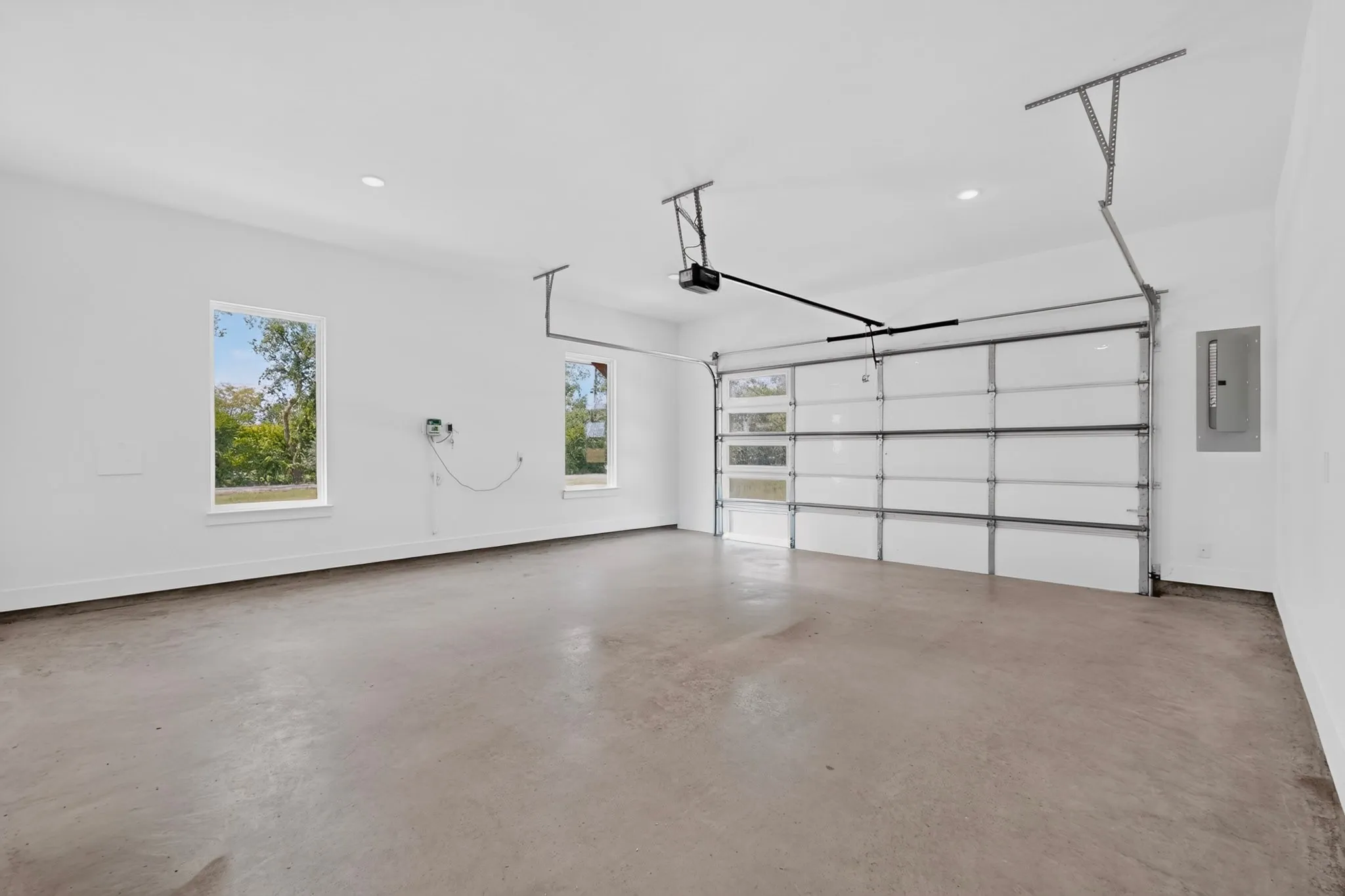 Spacious garage featuring a concrete floor, bright white walls, and two windows