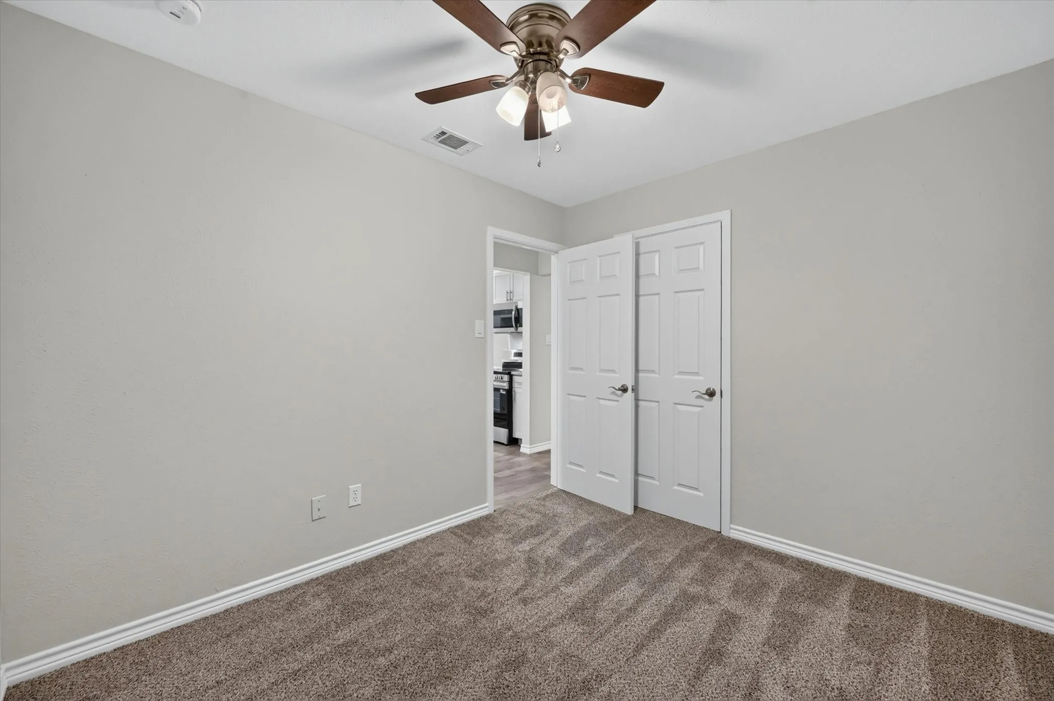Spacious room featuring neutral carpeting, light gray wall paint, and crisp white trim