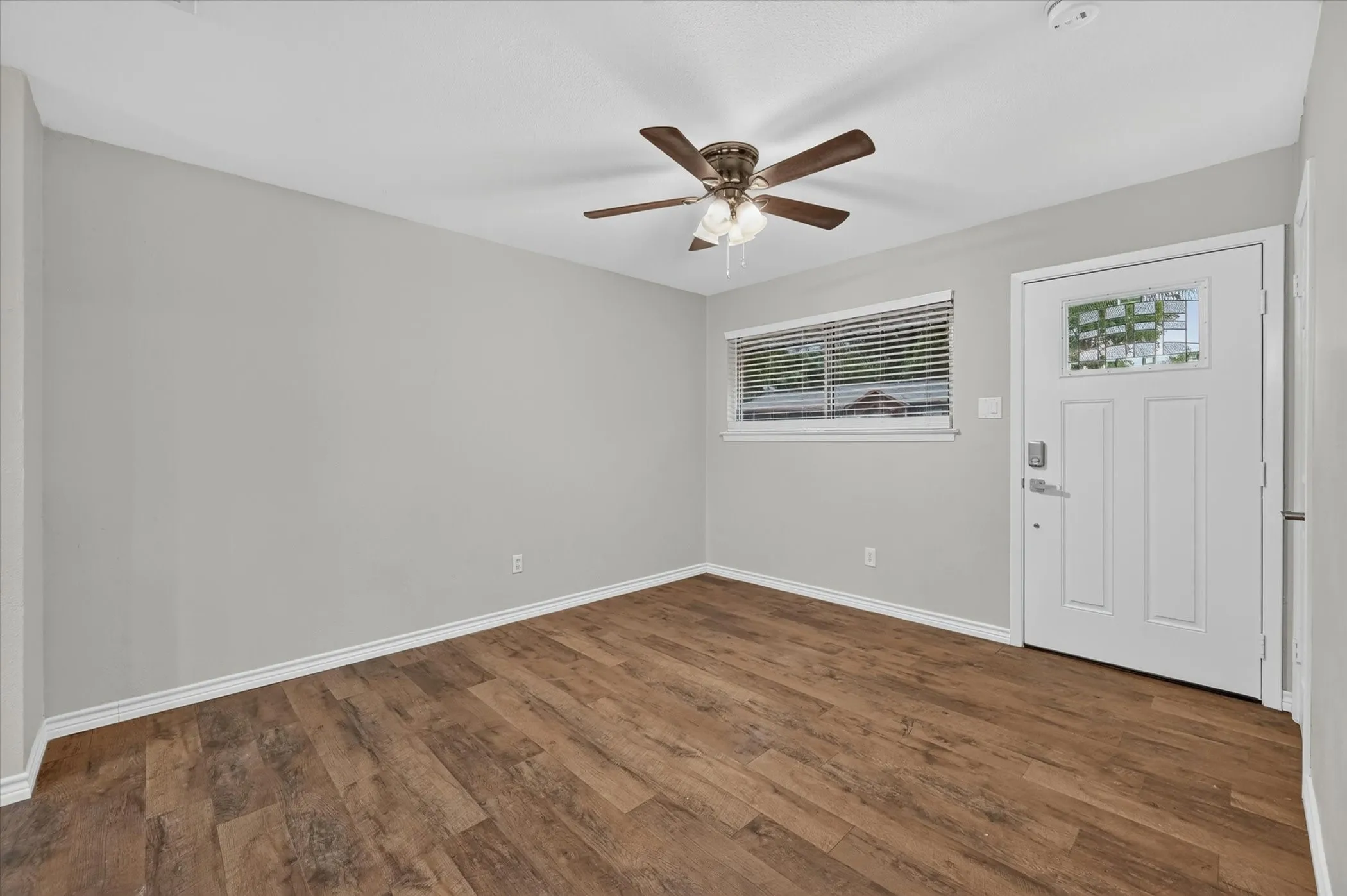 Room featuring wood-finish flooring, light grey walls, and white trim