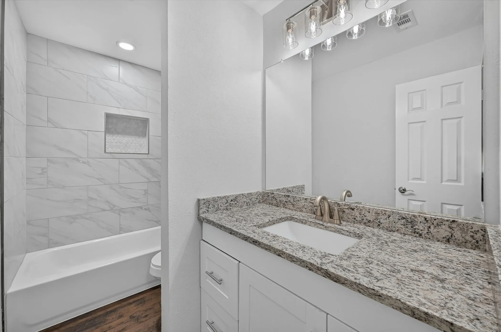 Bathroom featuring a single vanity with stone countertop, undermount sink, and brushed nickel faucet