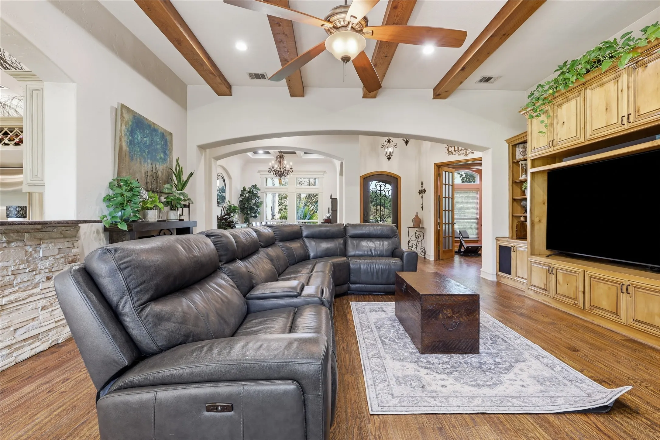 Living area featuring wood-finish flooring, exposed ceiling beams, and arched doorways