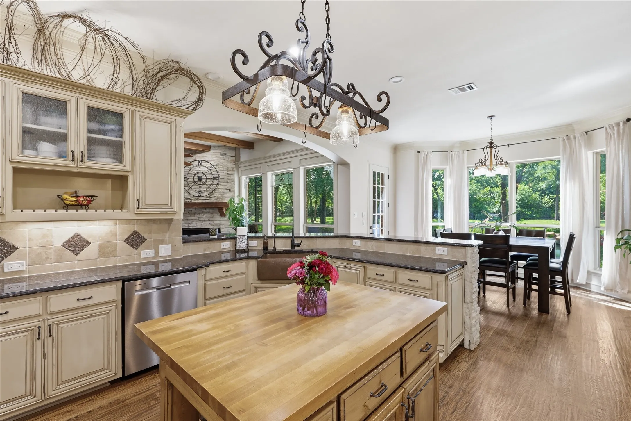 Open-concept kitchen featuring an island with a butcher block countertop, cream-colored cabinetry, stainless steel appliances, and granite countertops