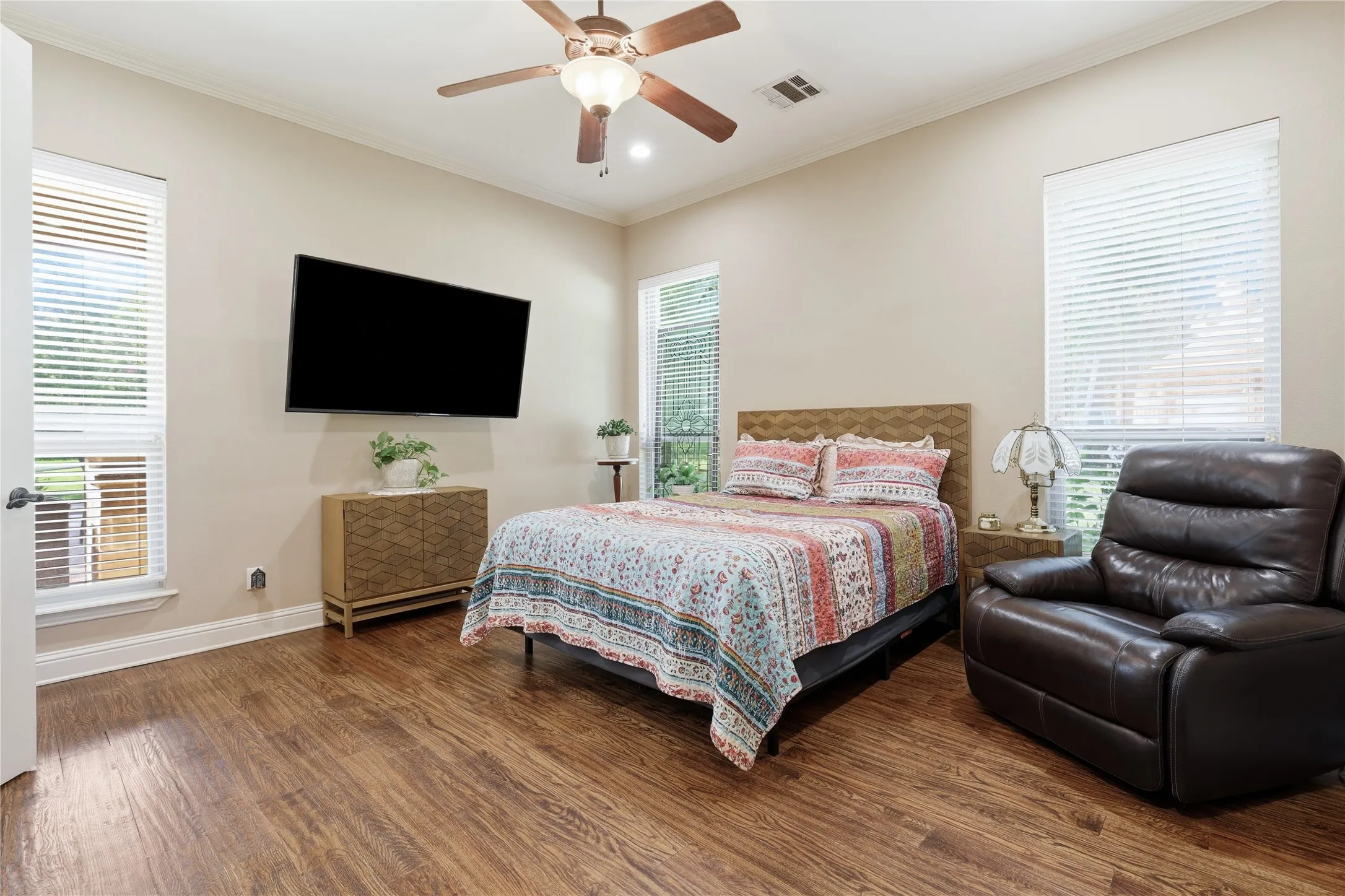 Guest suite with ensuite bathroom, Room featuring wood-finish flooring, a ceiling fan, and crown molding