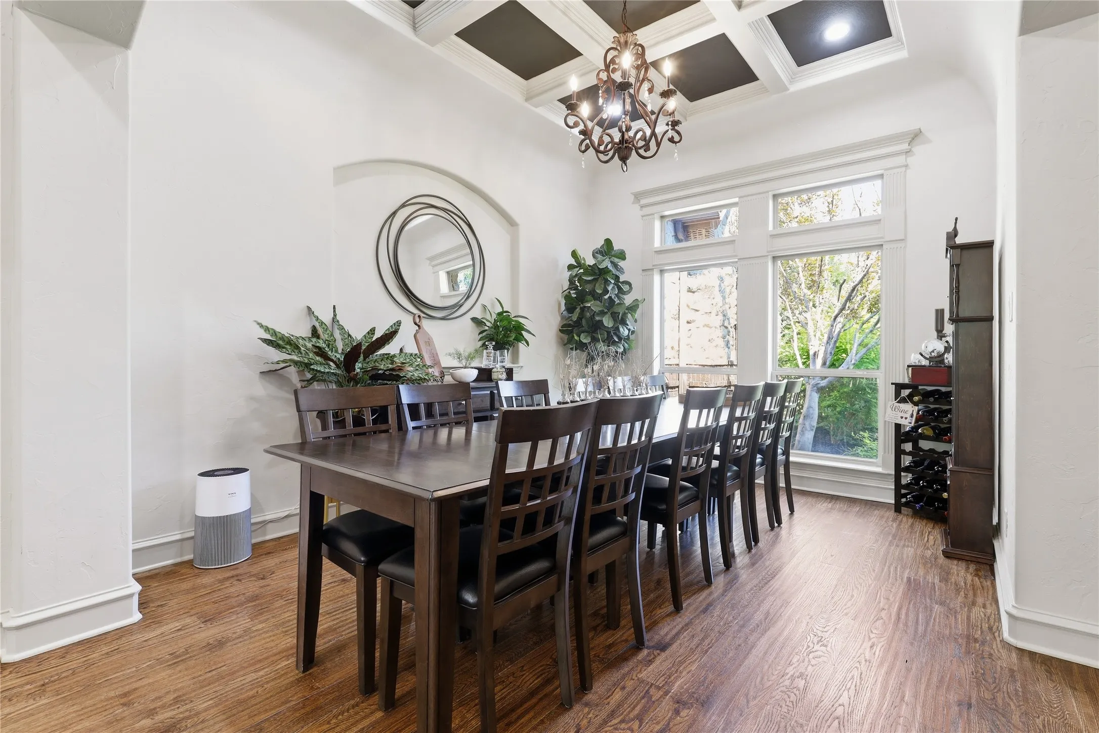 Formal dining area featuring rich wood-finish flooring, a coffered ceiling with recessed lighting, and a chandelier