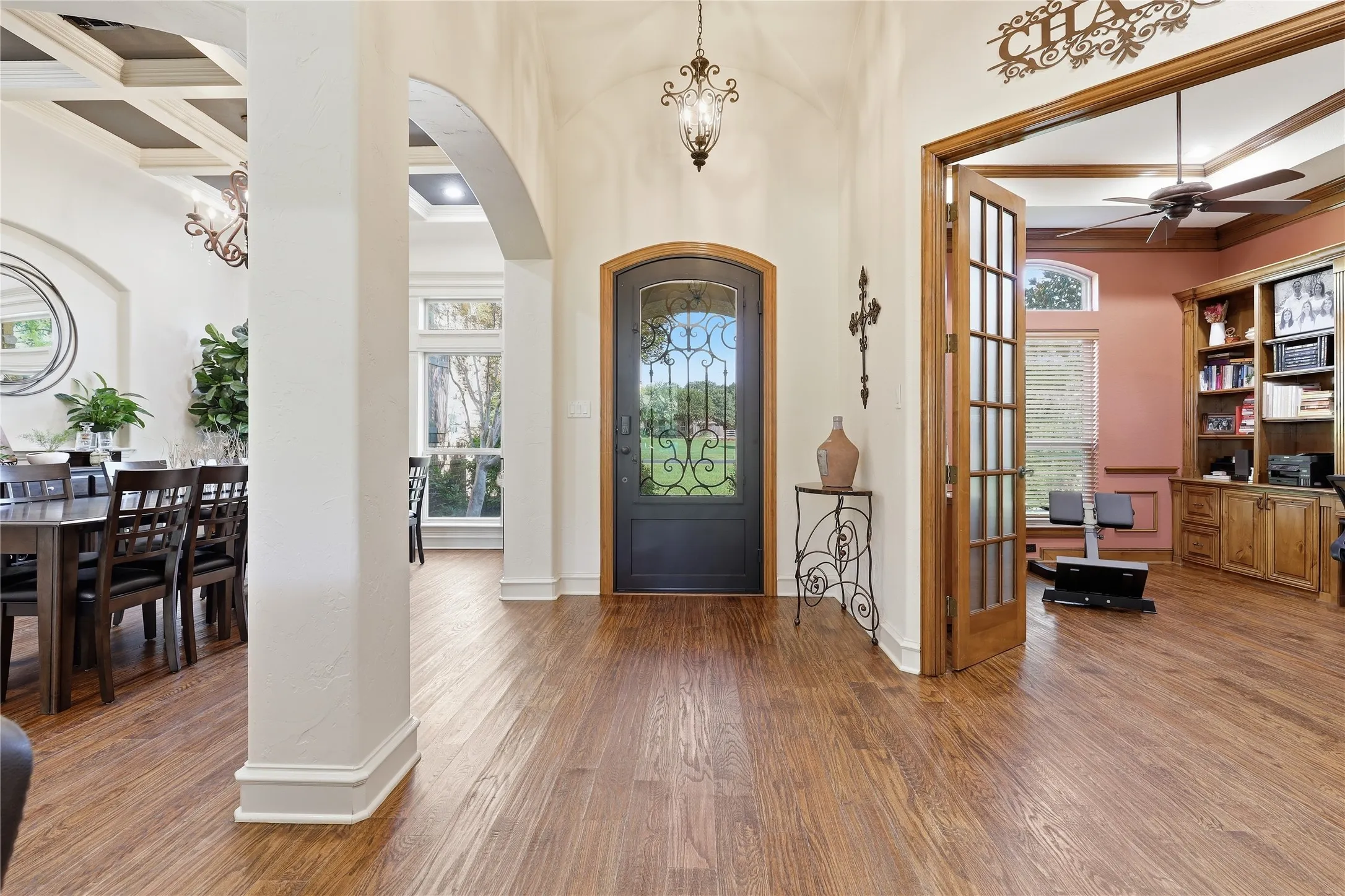 Entry foyer with wood-finish flooring, an arched doorway, and an ornate ceiling fixture