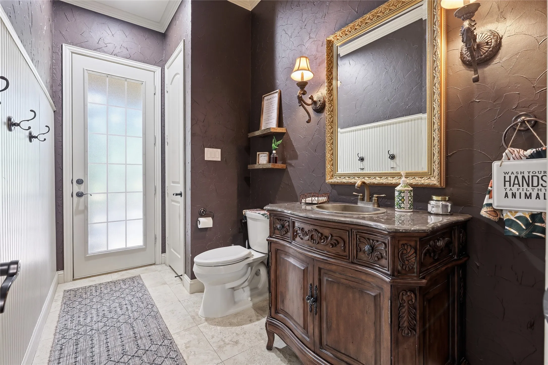 Powder room leading from the hallway and into the outdoors, Ornate wood-carved vanity with a stone countertop and undermount sink
