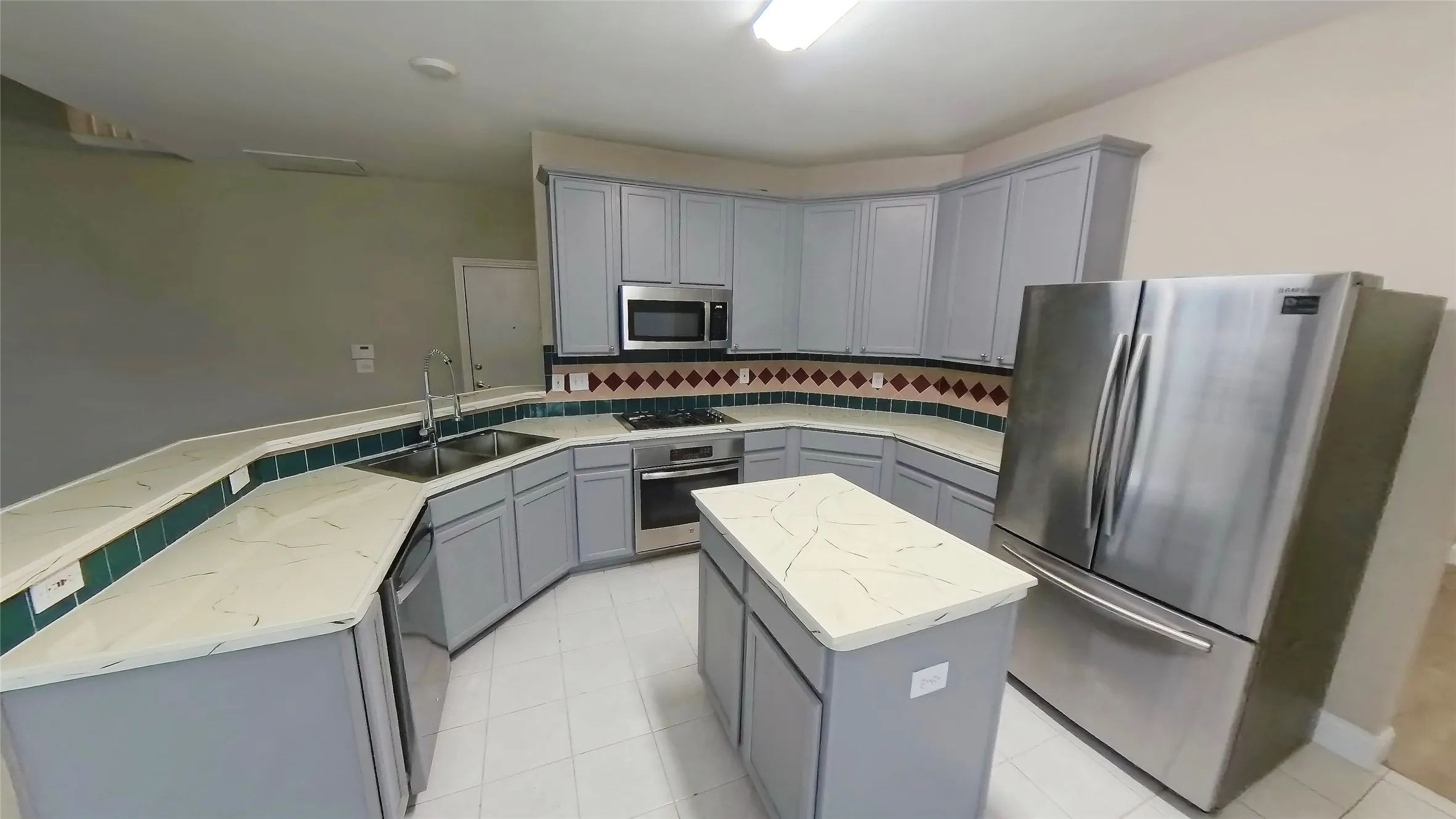Kitchen featuring sink, a center island, stainless steel appliances, gray cabinets, and decorative backsplash