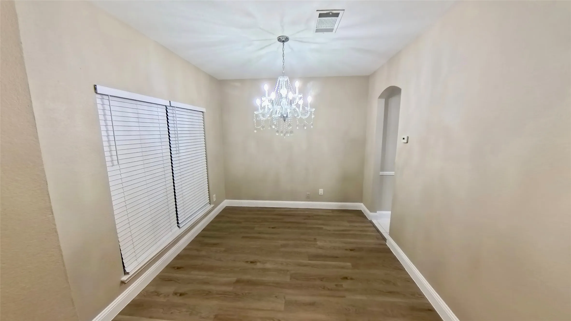Unfurnished dining area featuring dark wood-type flooring and a chandelier