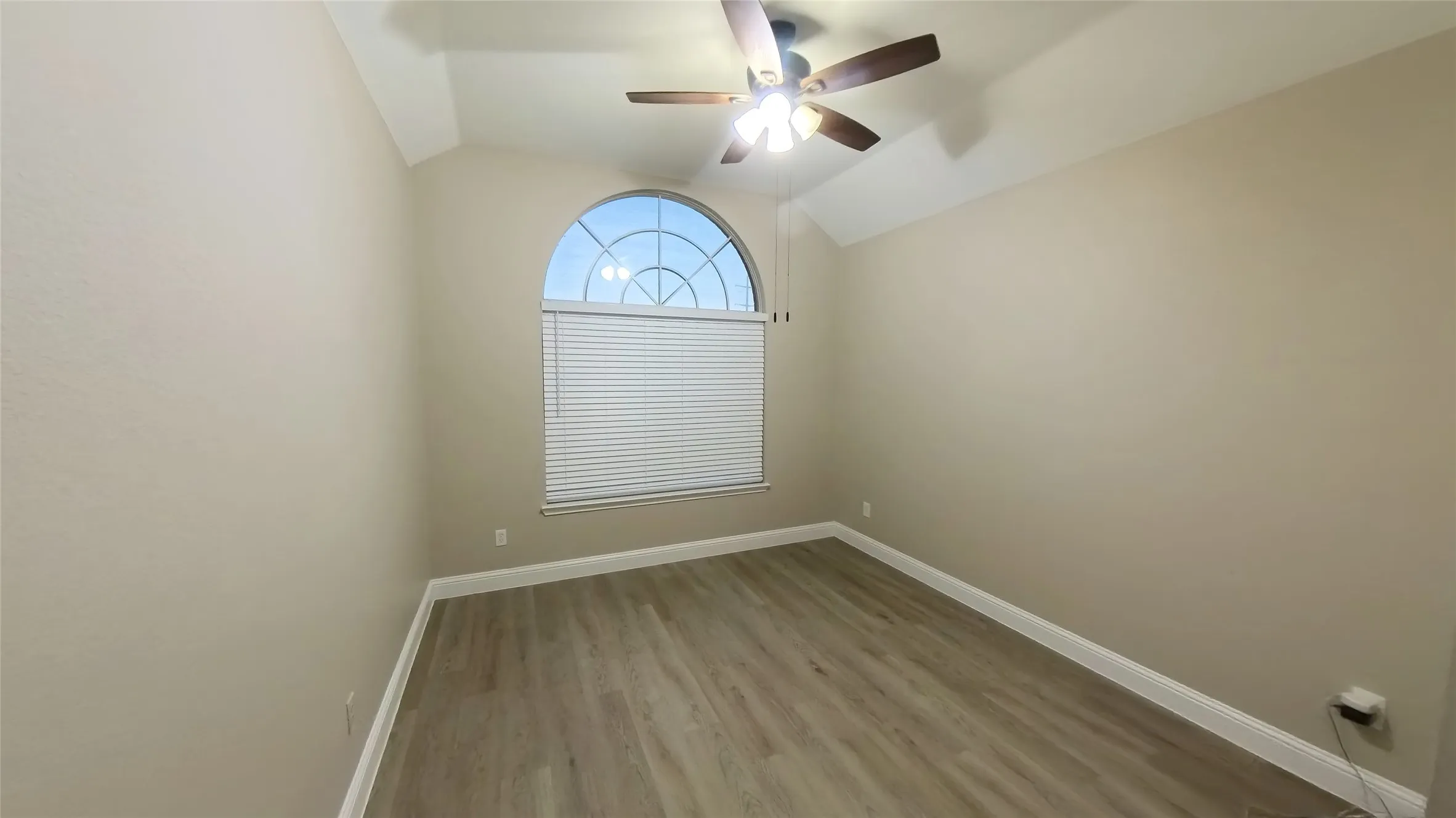 Empty room featuring ceiling fan, vaulted ceiling, and hardwood / wood-style flooring
