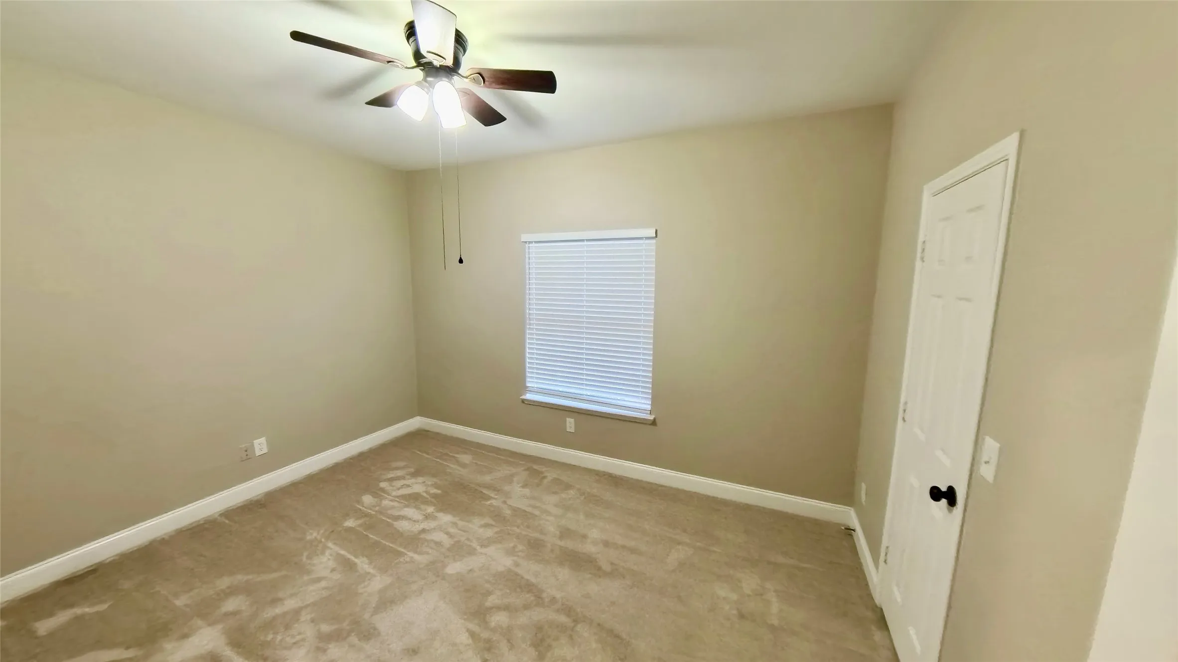 Spare room featuring light colored carpet and ceiling fan
