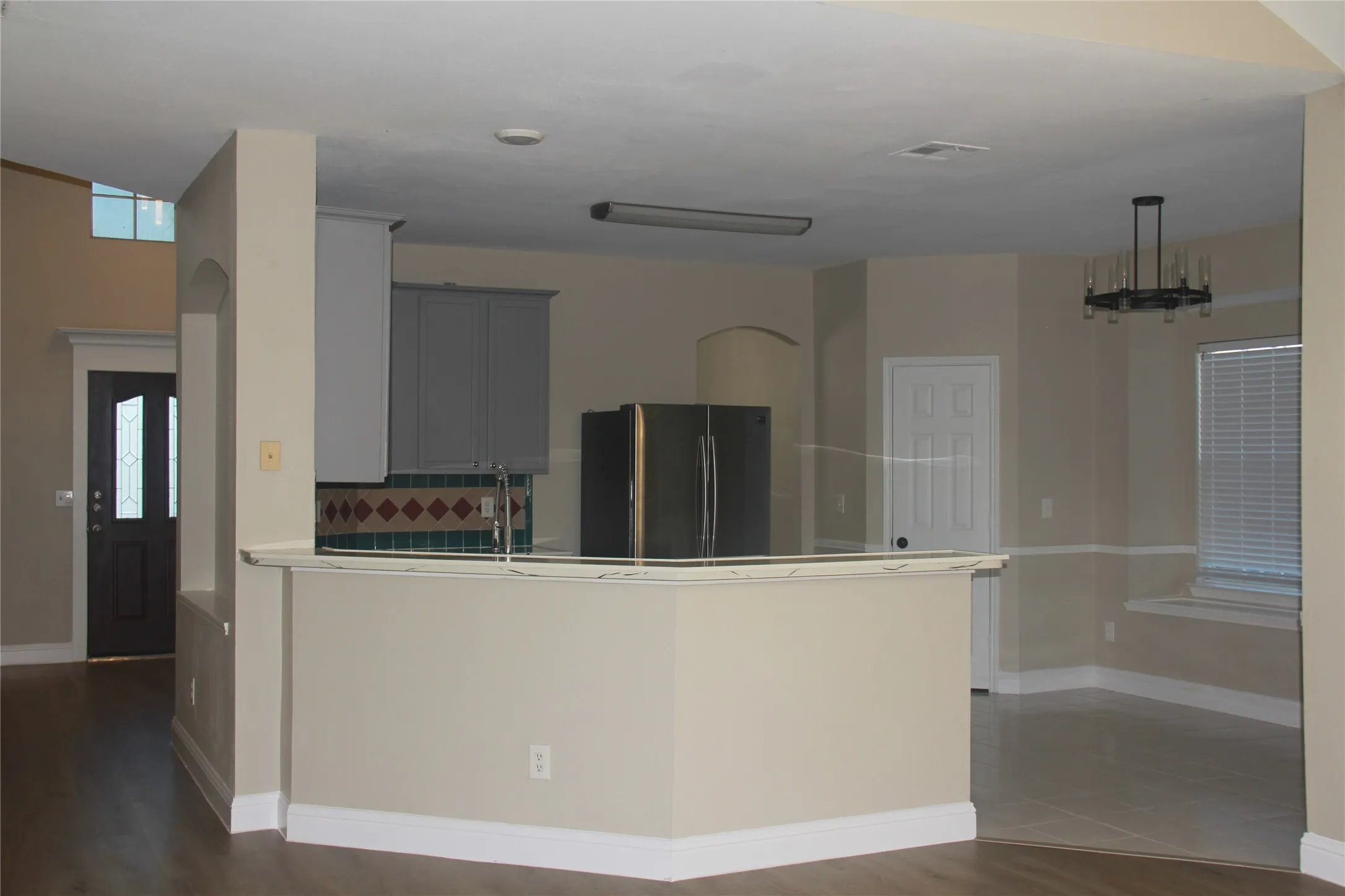 Kitchen with backsplash, dark wood-type flooring, sink, gray cabinets, and stainless steel refrigerator