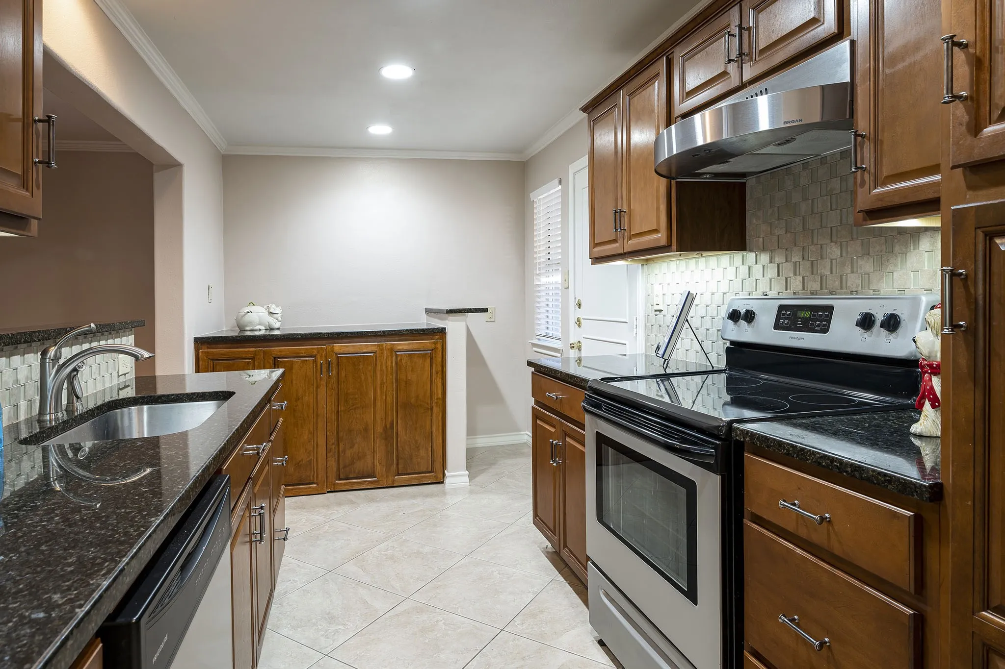 Open Kitchen design with stainless steel sink, granite counters, with a full-size washer and dryer hidden within a custom cabinet