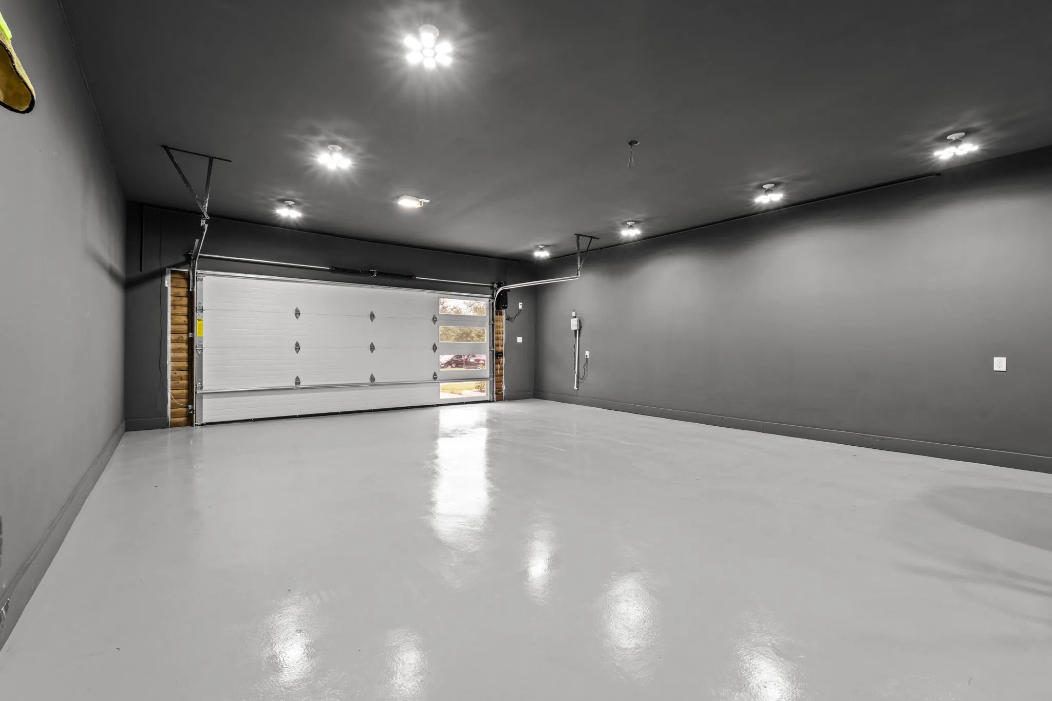 Spacious garage featuring a light gray epoxy floor and dark gray walls