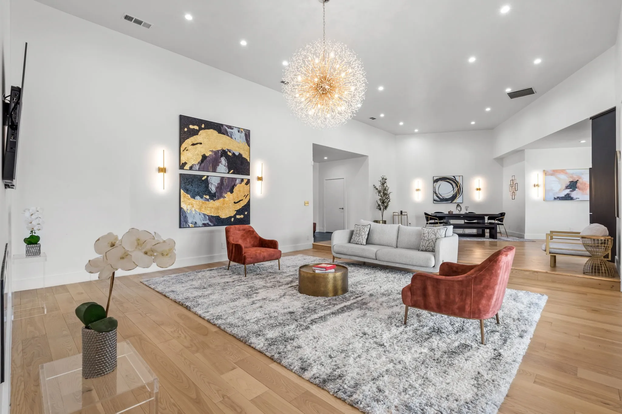 Spacious living area featuring high ceilings, wood-finish flooring, recessed lighting, and a prominent chandelier