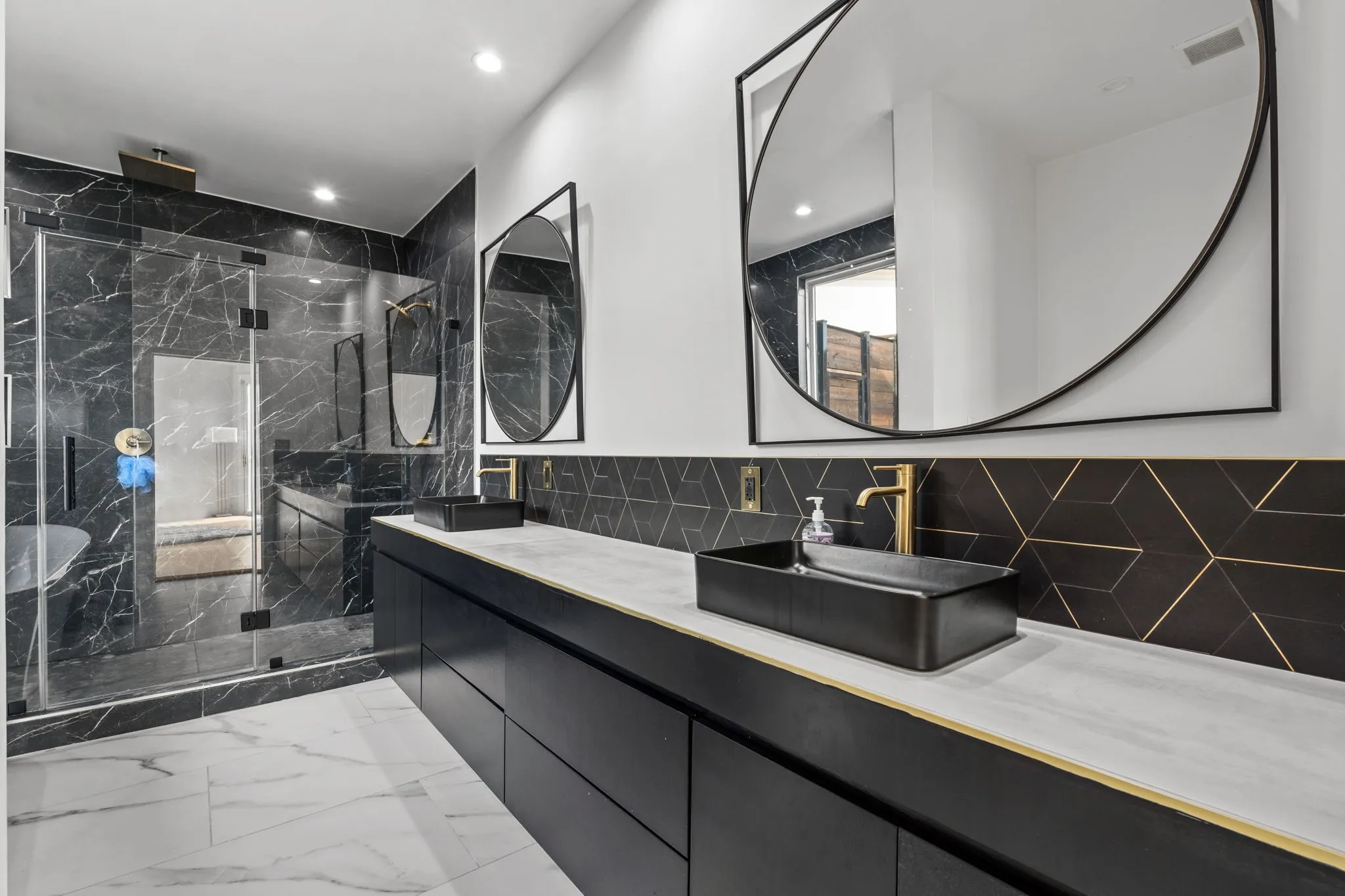 Primary Bathroom featuring a dual vanity with rectangular vessel sinks, gold-finish fixtures, and a geometric tile backsplash