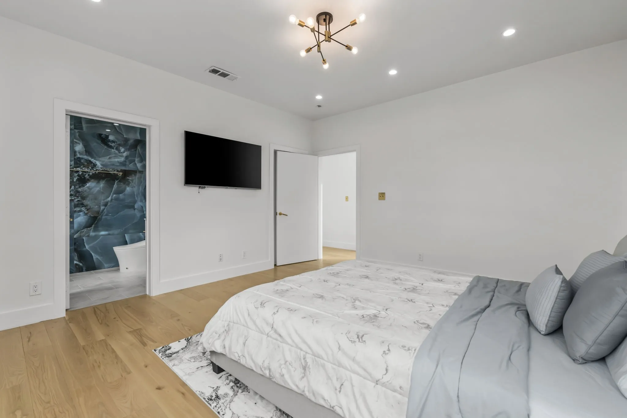 Spacious room with light wood-finish flooring, recessed lighting, and a contemporary ceiling fixture