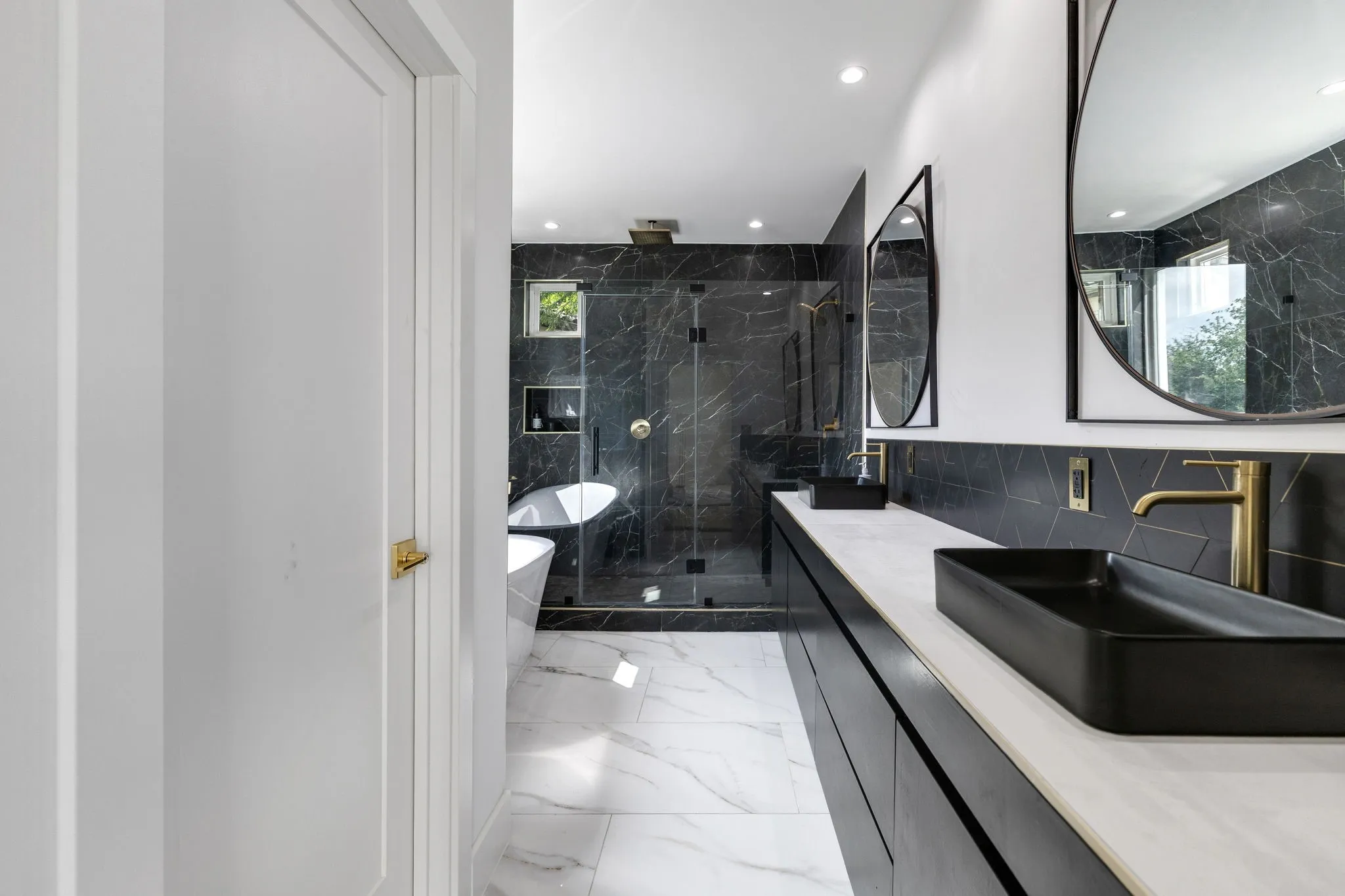 Luxurious bathroom featuring a dual vanity with rectangular vessel sinks, gold-finish fixtures, and a freestanding soaking tub