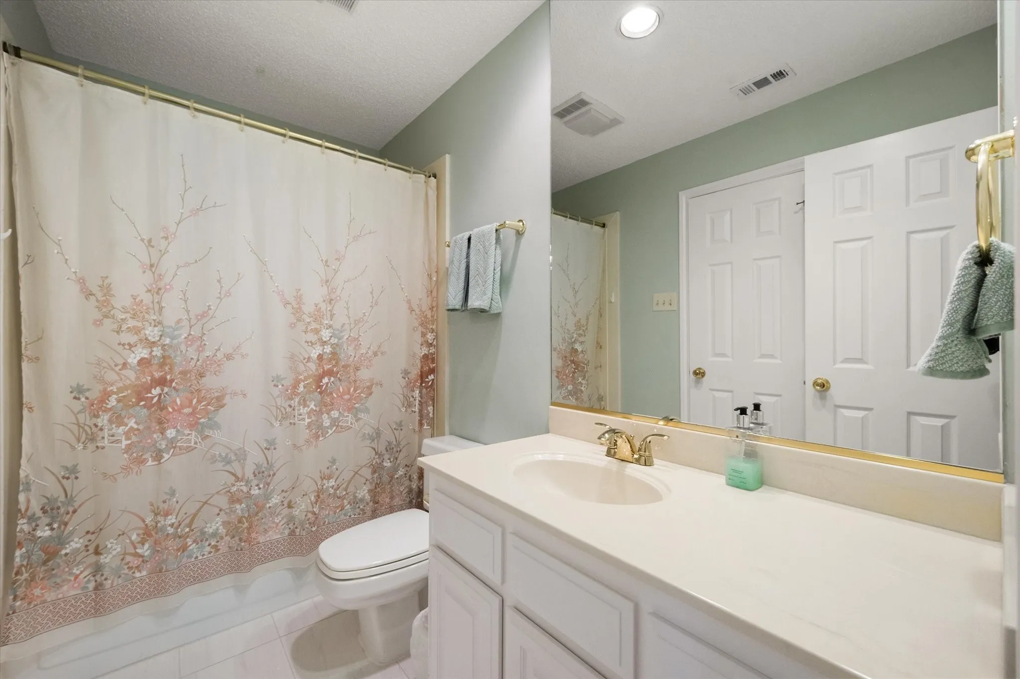 Guest bathroom featuring a vanity with a gold-toned faucet, and tub shower