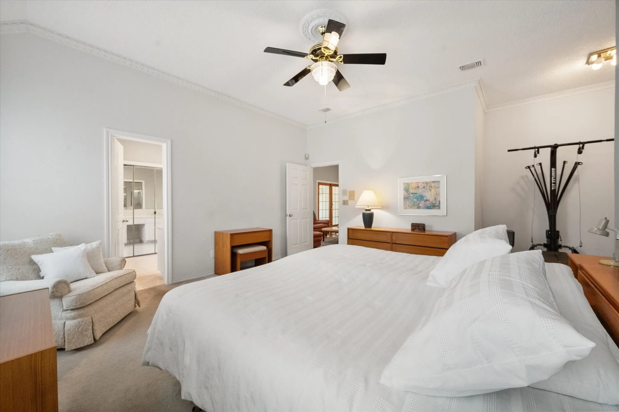 Spacious room with a ceiling fan, crown molding, and separate sitting or workout area