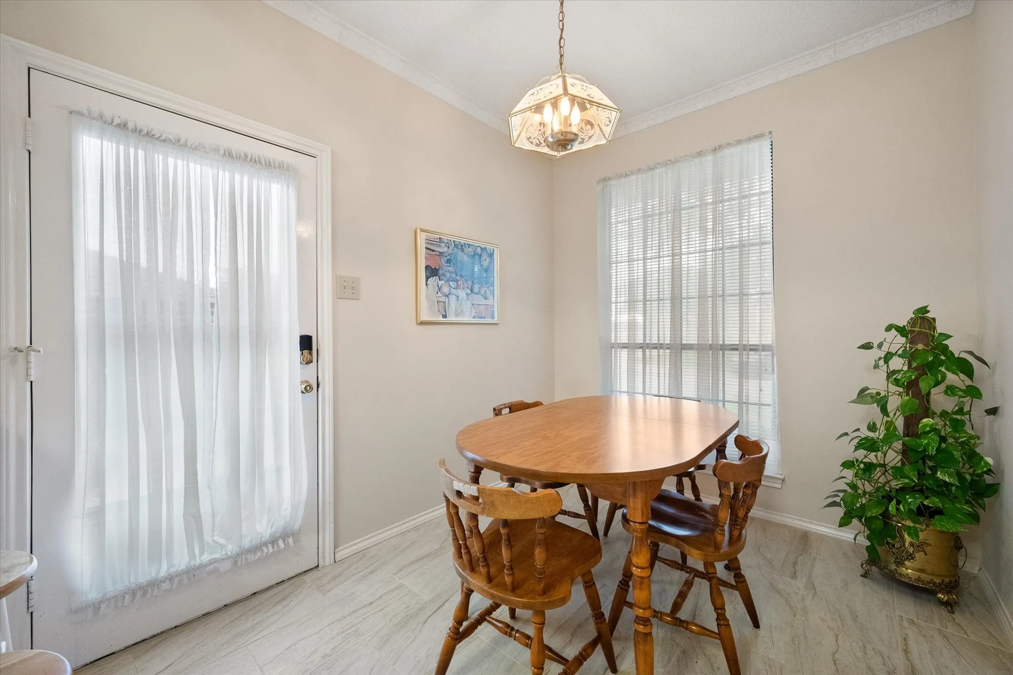 Bright dining area featuring a pendant light fixture, crown molding, and wood-finish flooring