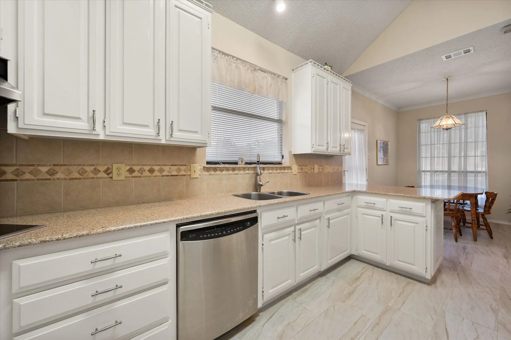 Kitchen featuring white cabinetry, stone-look countertops, a tile backsplash with decorative accents, stainless steel dishwasher, and wood-finish flooring