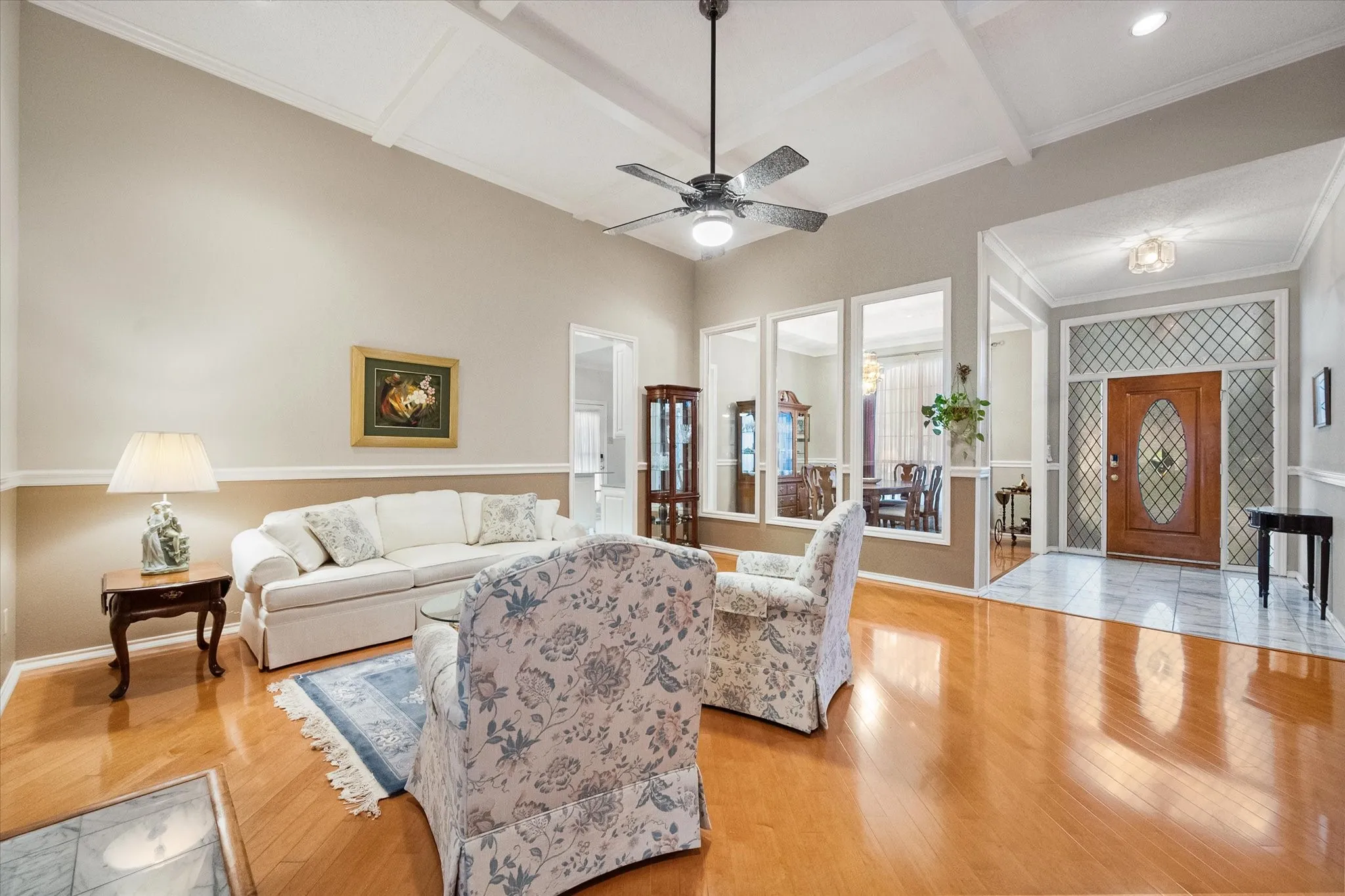 Spacious living area featuring wood-finish flooring, a coffered ceiling, and a ceiling fan