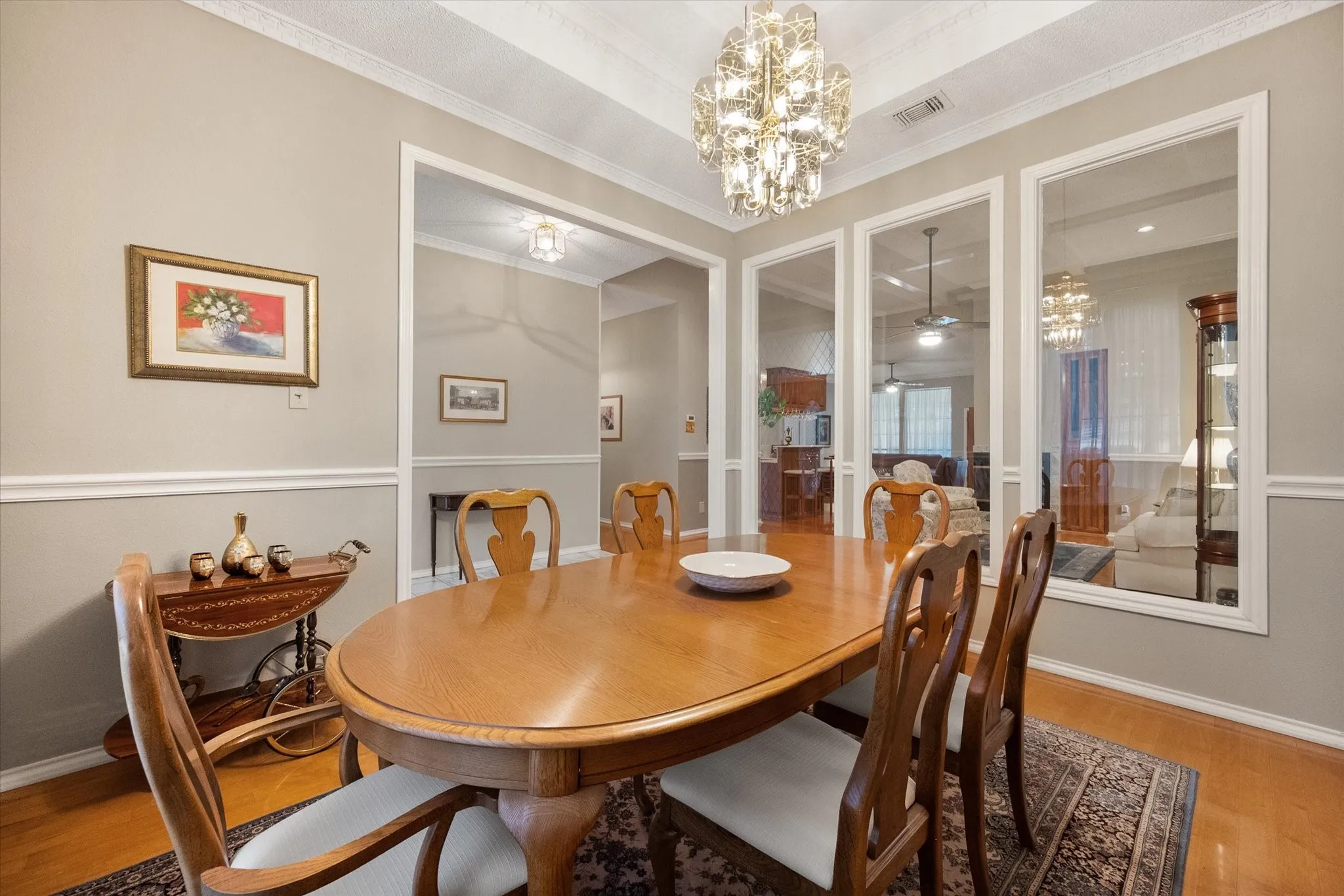 Formal dining area featuring hardwood flooring, crown molding, chair rail, and a contemporary chandelier