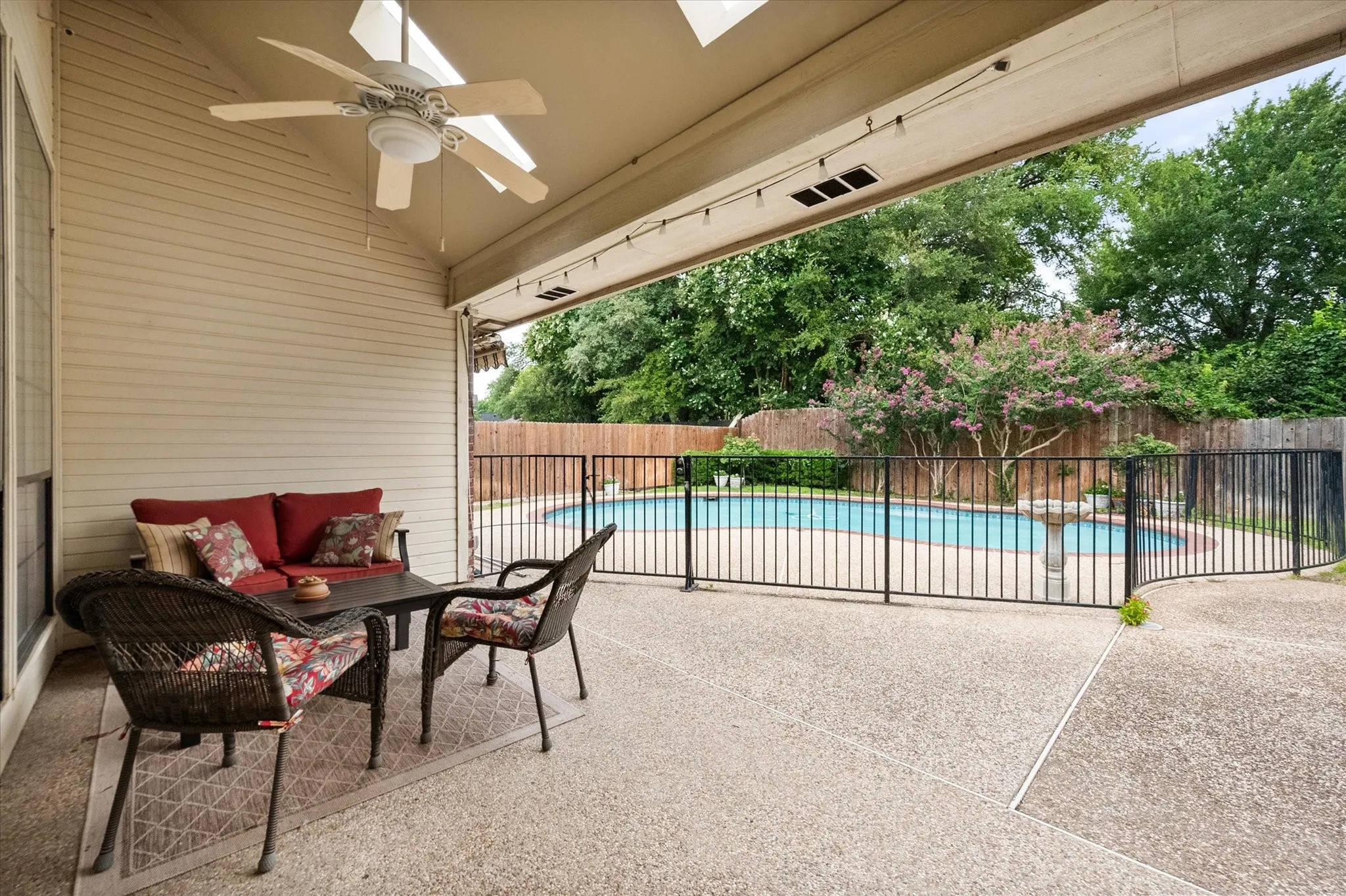 Spacious covered patio with ceiling fan, motorized awning, featuring an exposed aggregate concrete surface