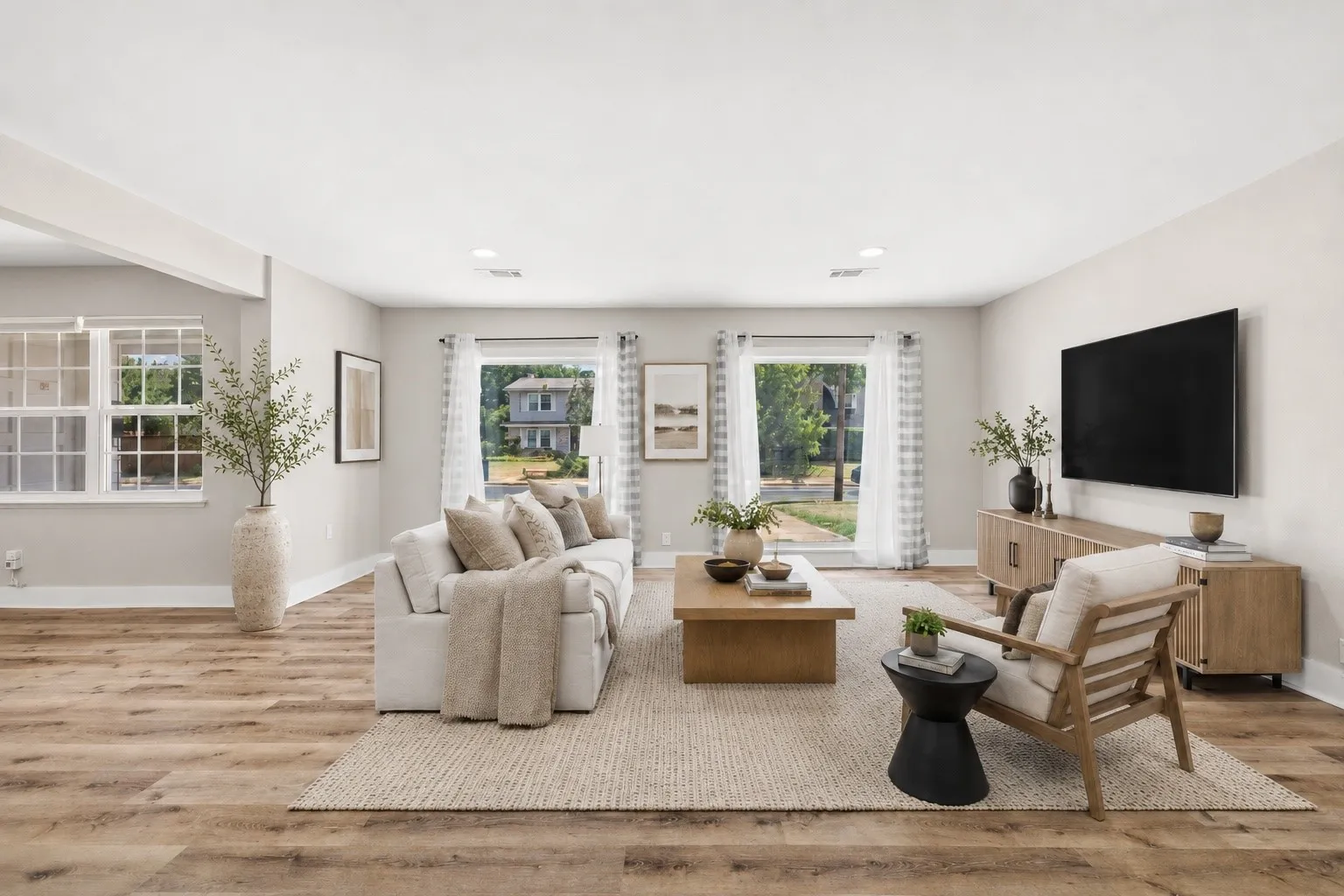 Spacious living area featuring wood-finish flooring, recessed lighting, and ample natural light from multiple windows