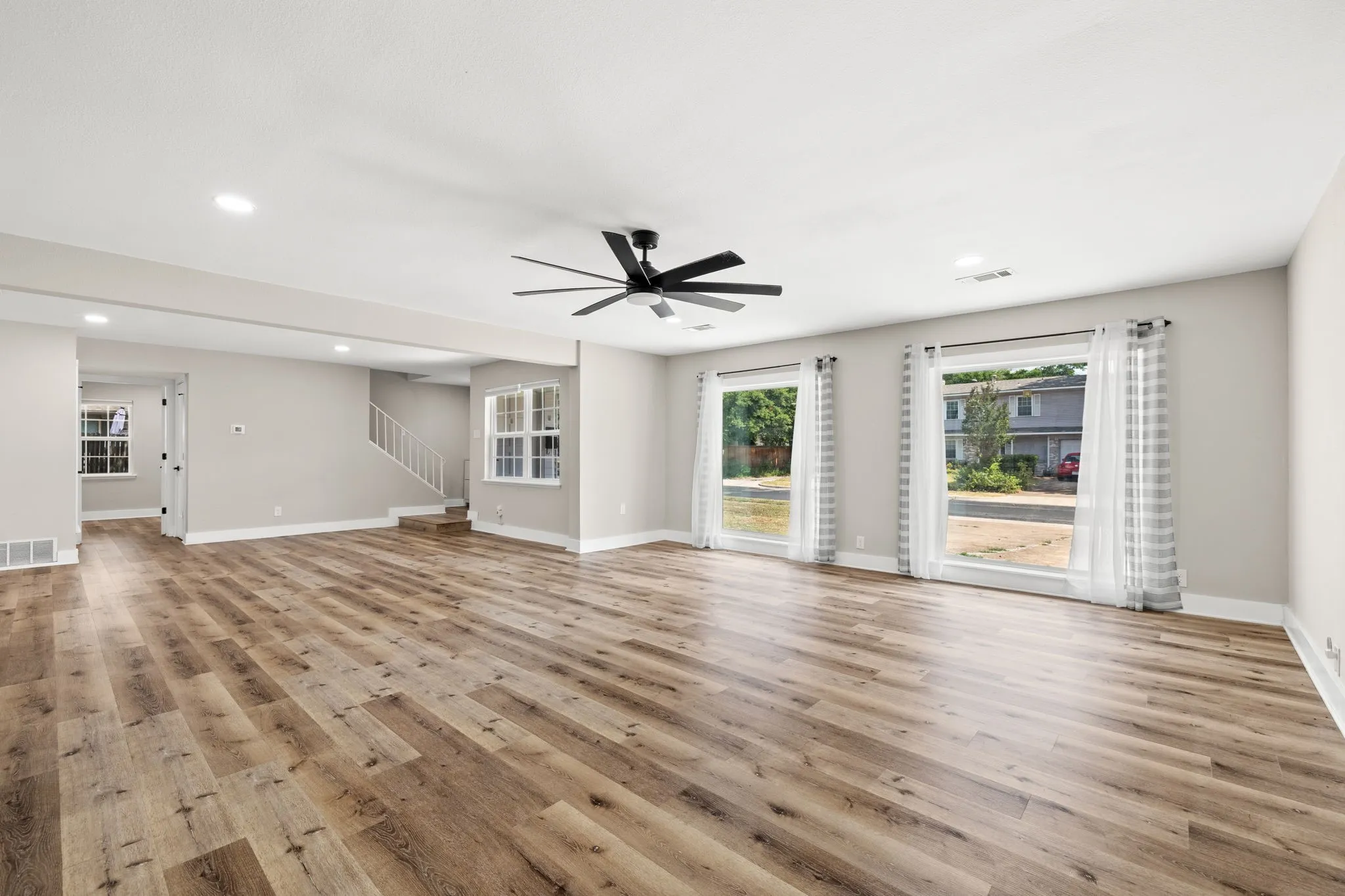 Spacious room featuring wood-finish flooring, recessed lighting, and a contemporary ceiling fan