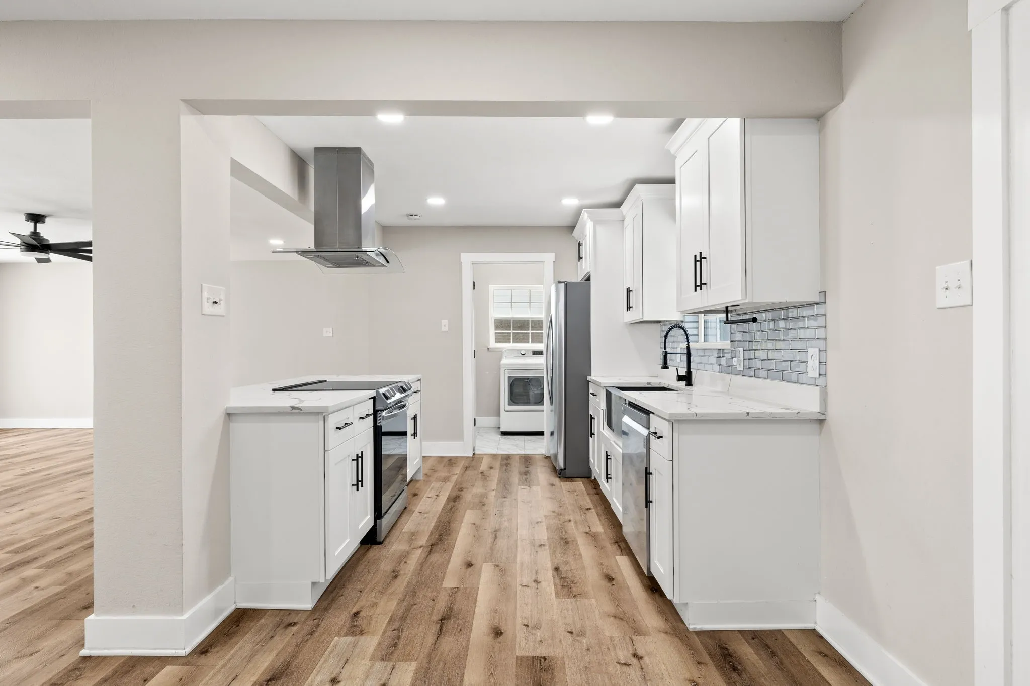 Contemporary kitchen featuring white cabinetry, light-toned countertops, and a subway tile backsplash