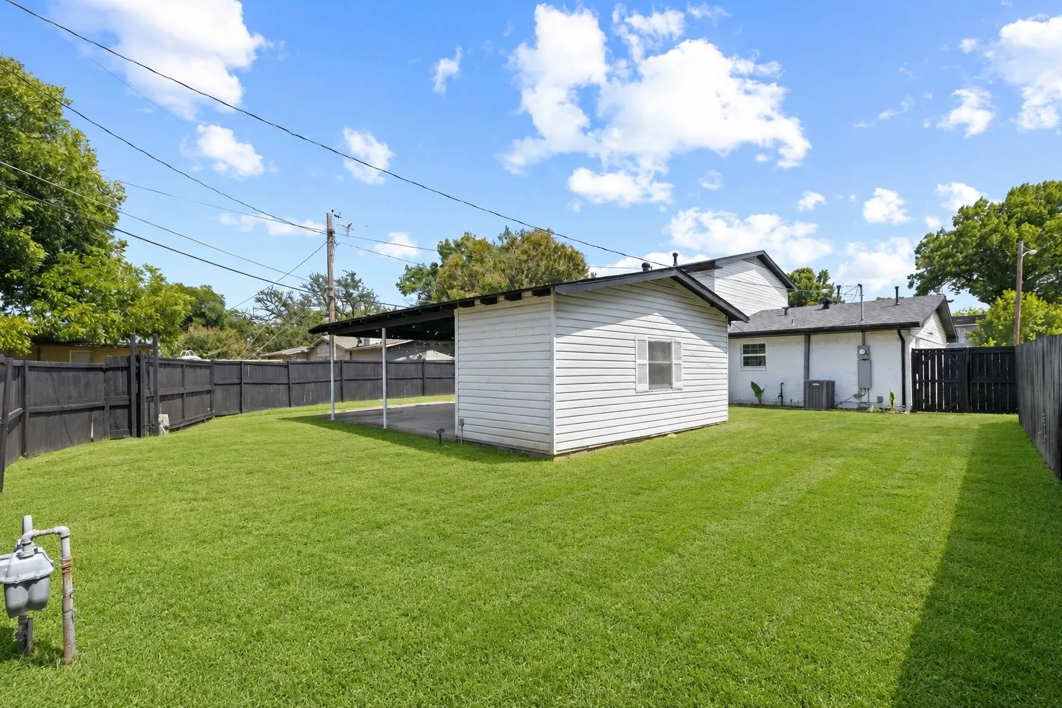Expansive green lawn with a detached shed featuring white siding and a window