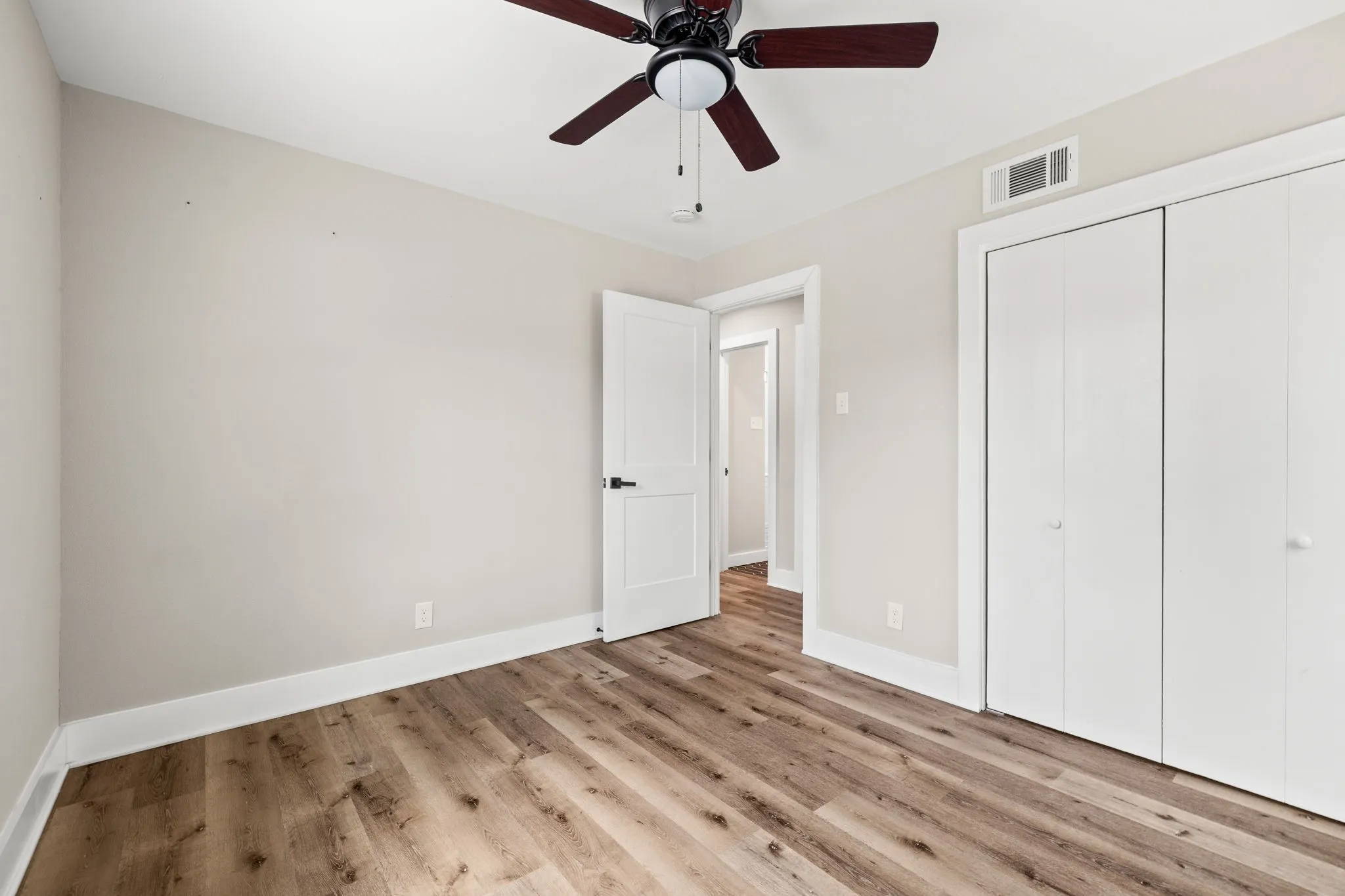 Neutral-toned interior with wood-finish flooring, a ceiling fan, and white baseboards