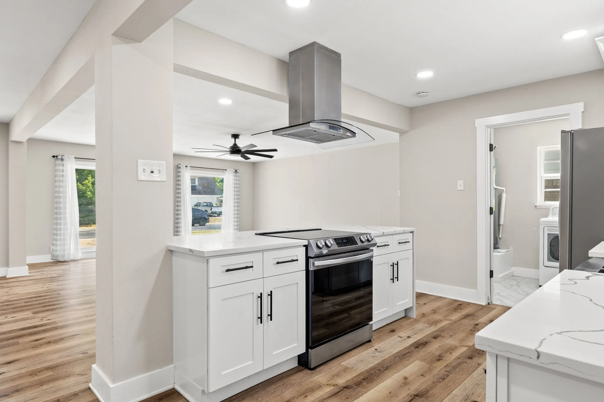 Kitchen featuring a stainless steel range with overhead vent, white cabinetry, and light-toned countertops